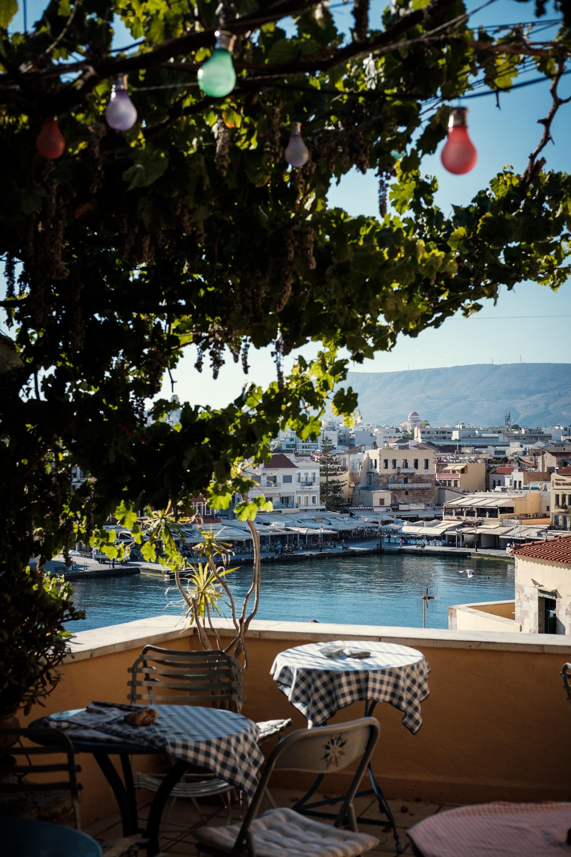 cafe table on balcony shadowed by tree overlooking island town