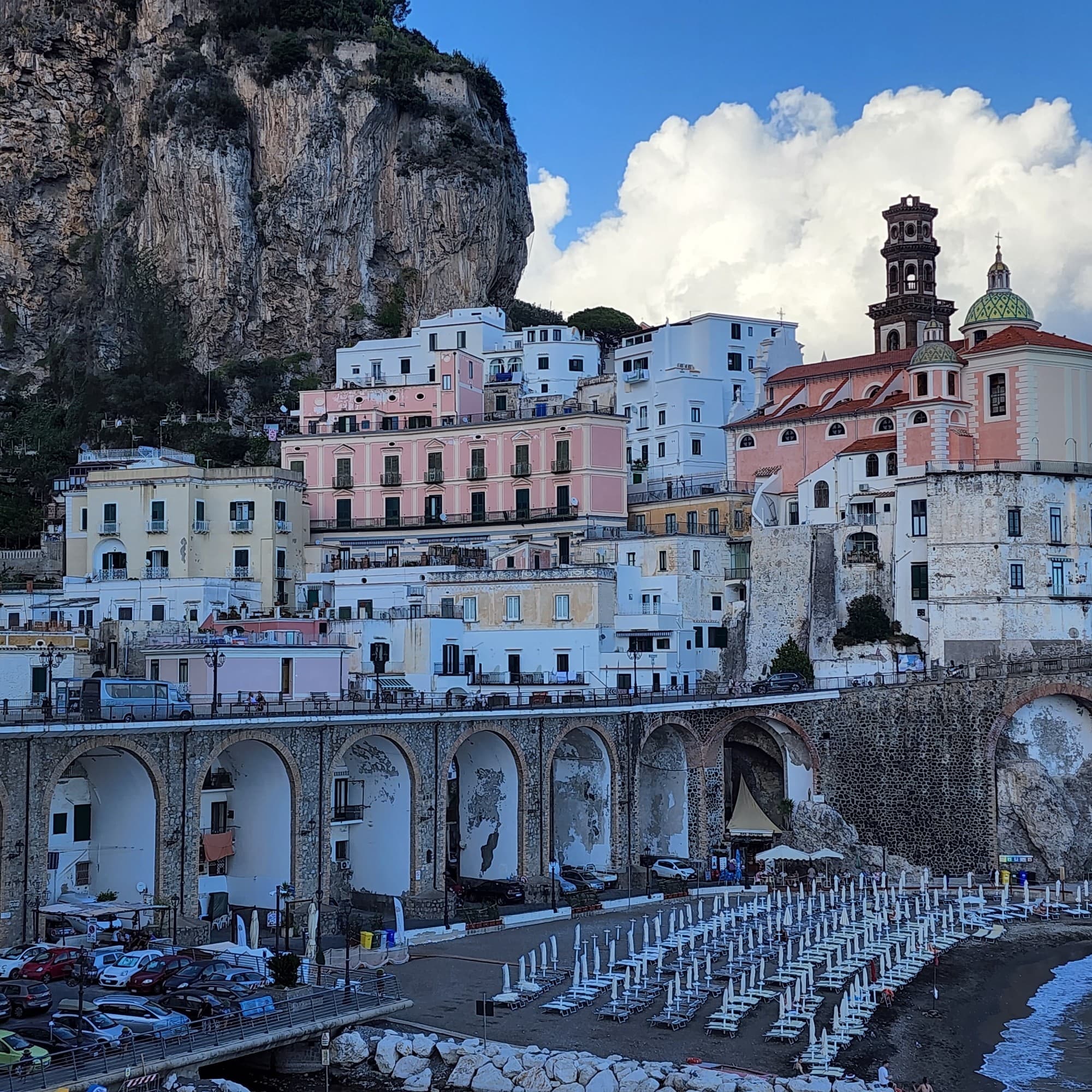 View of colorful buildings with mountains at sea shore.