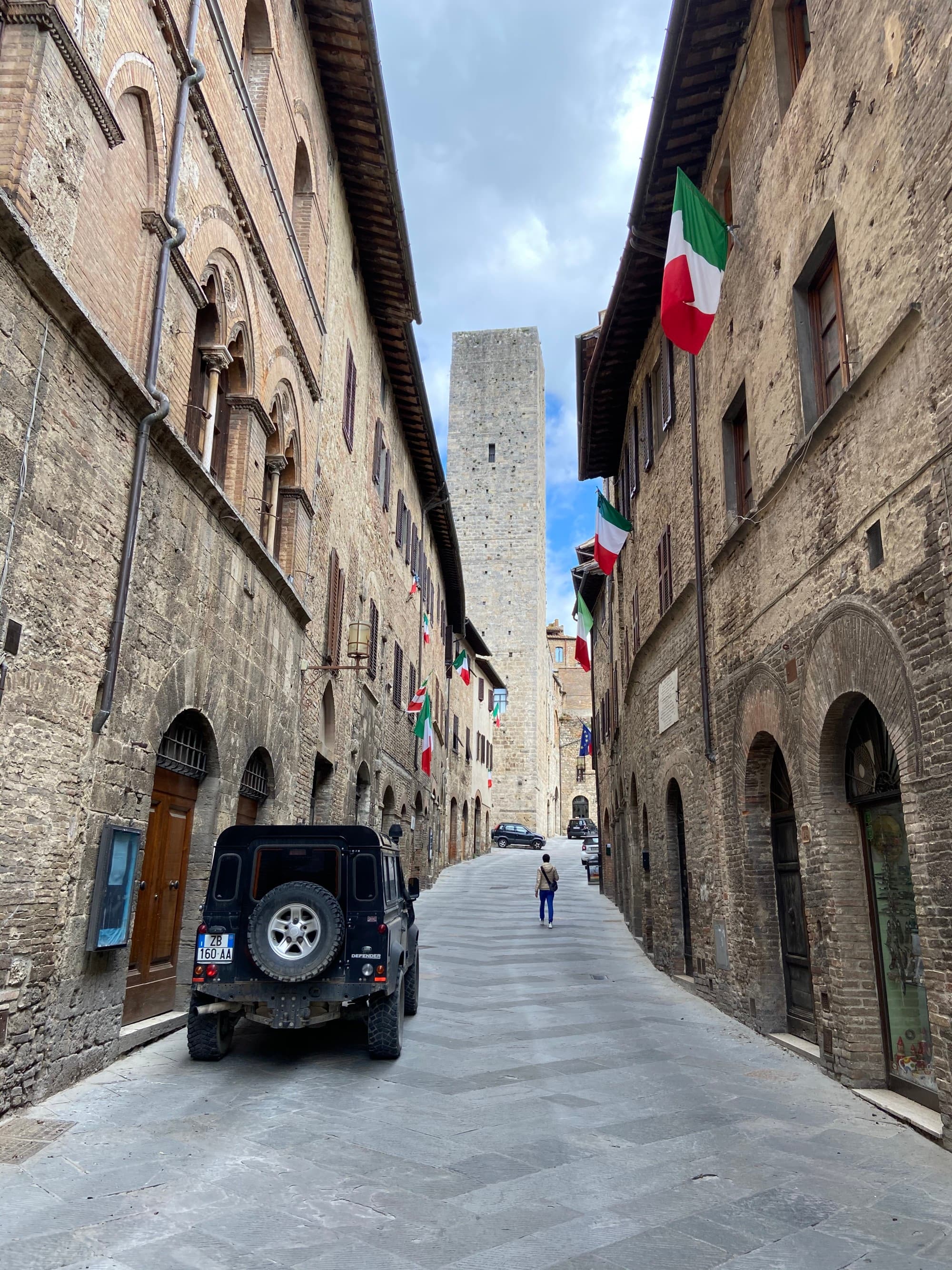 A narrow street with buildings with flags on both sides.