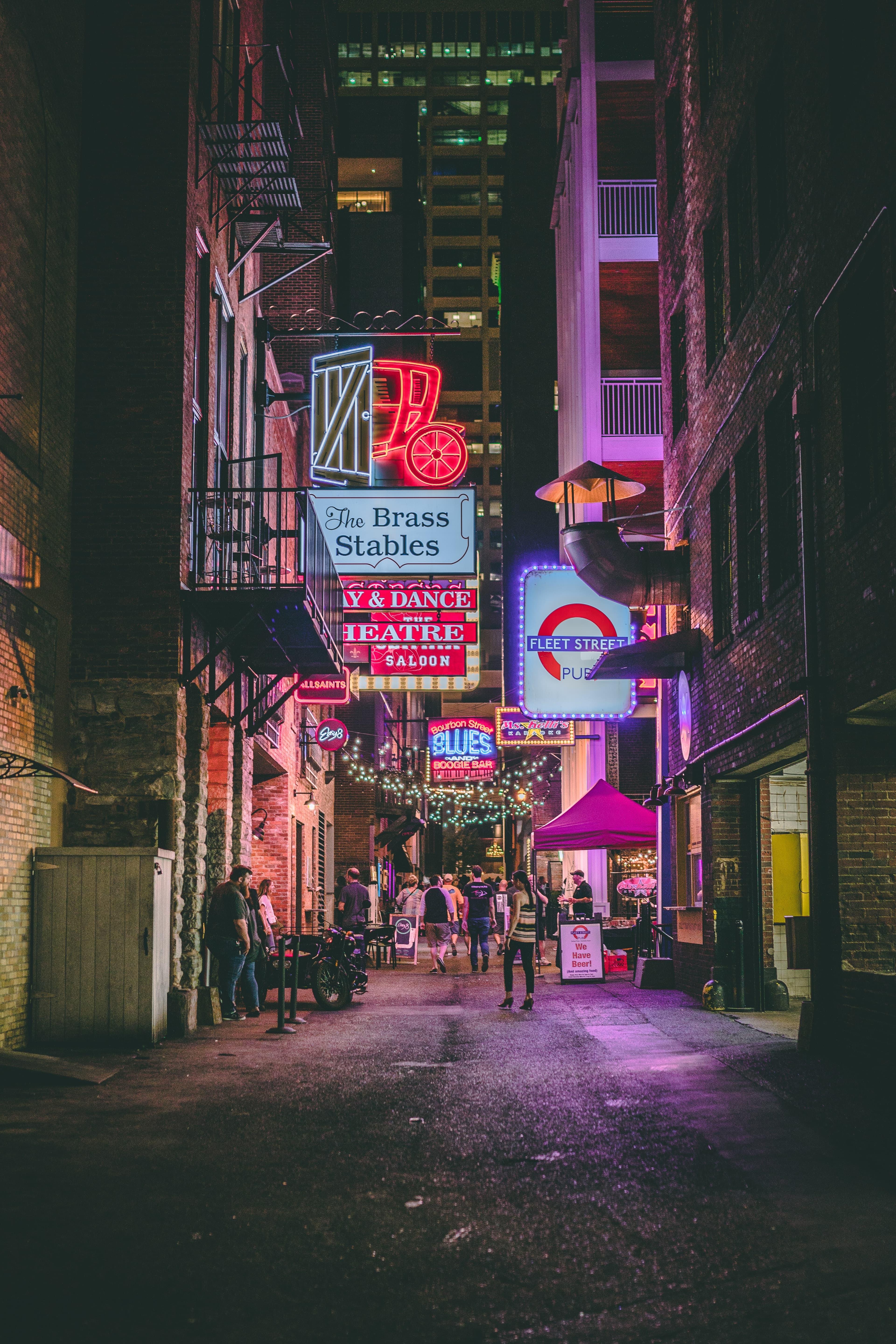 Bright signs with people walking on sidewalk at night