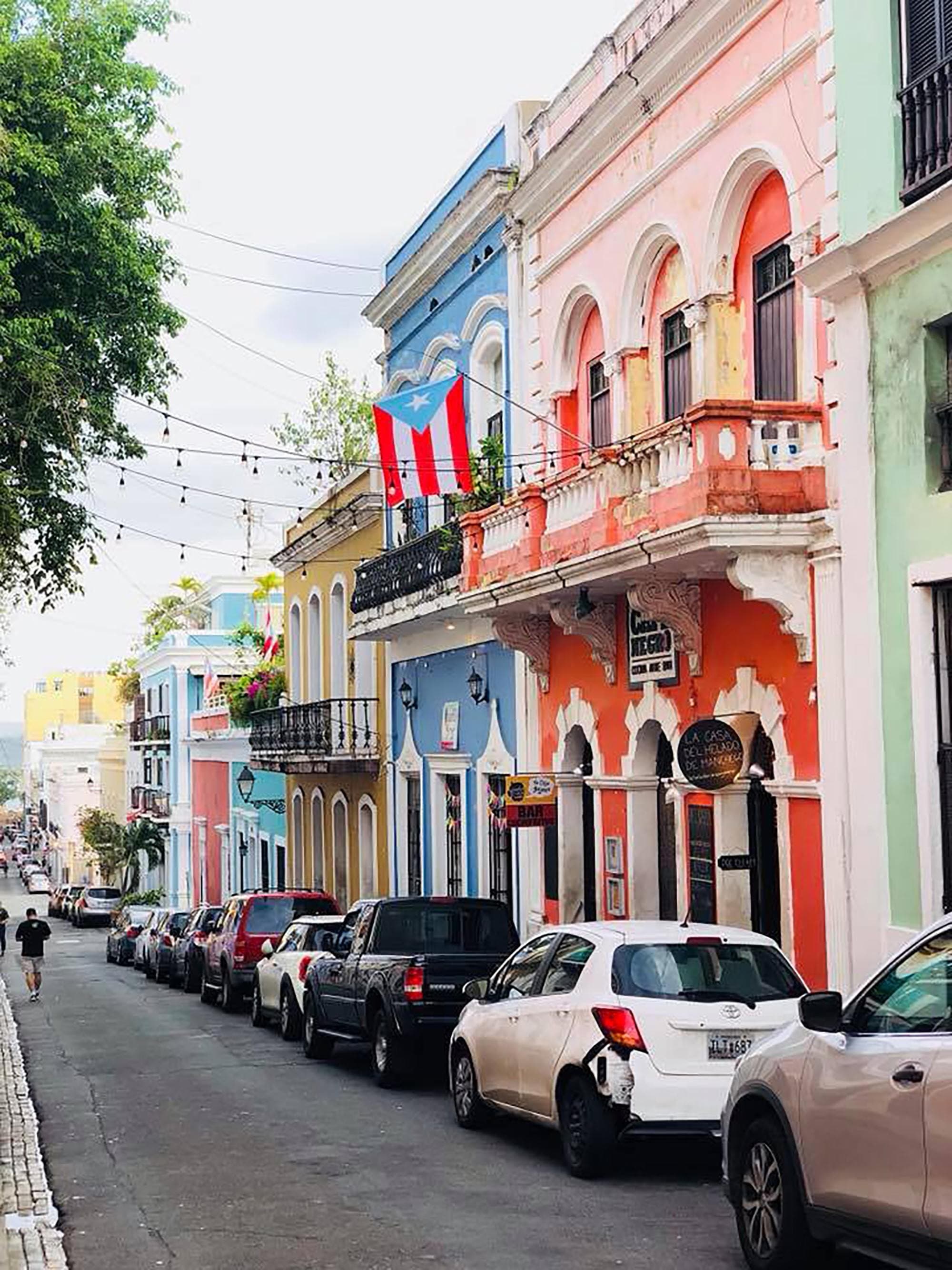 colorful houses with balconies line a street parked with cars