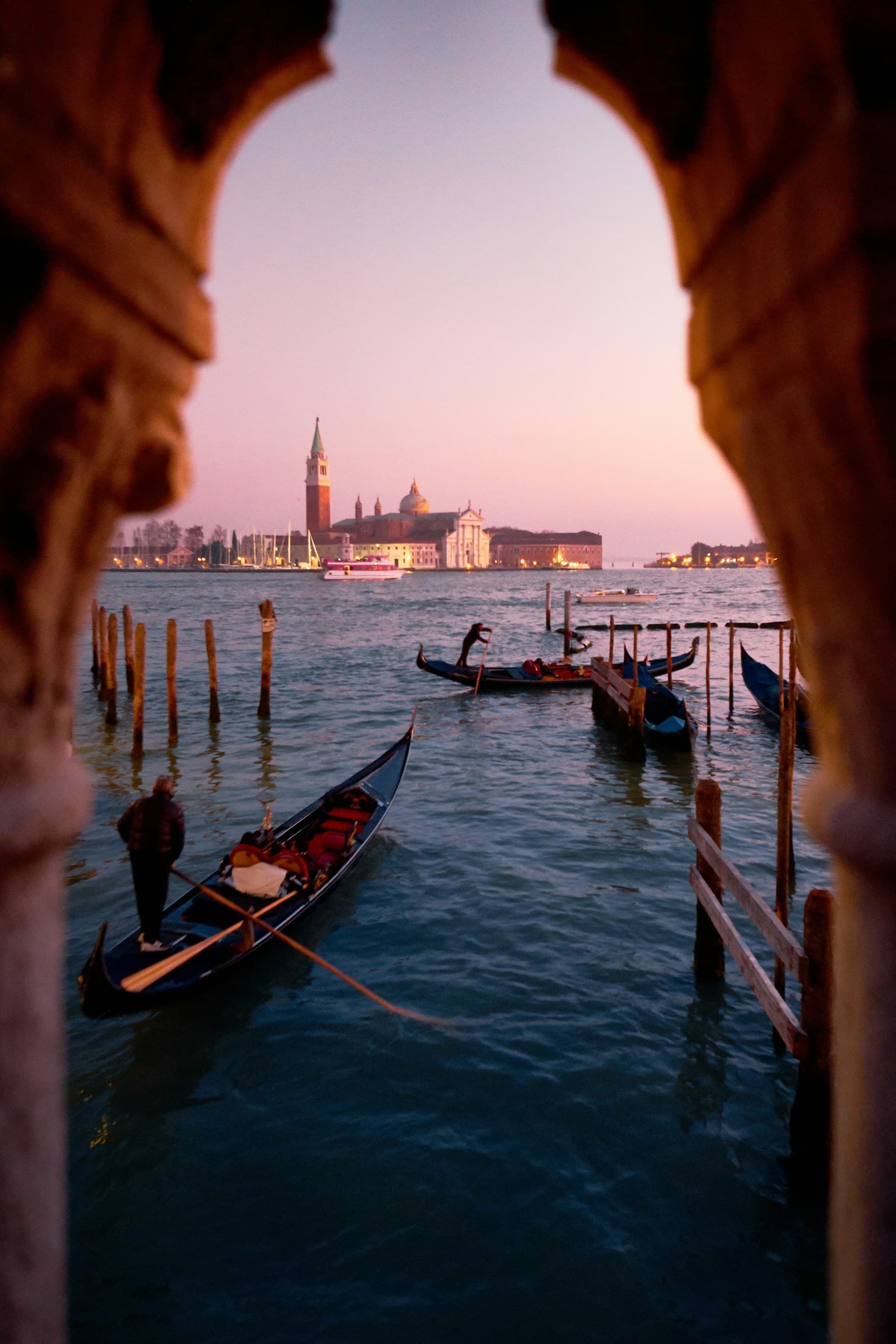 A picture of a canal through an arch during daytime.