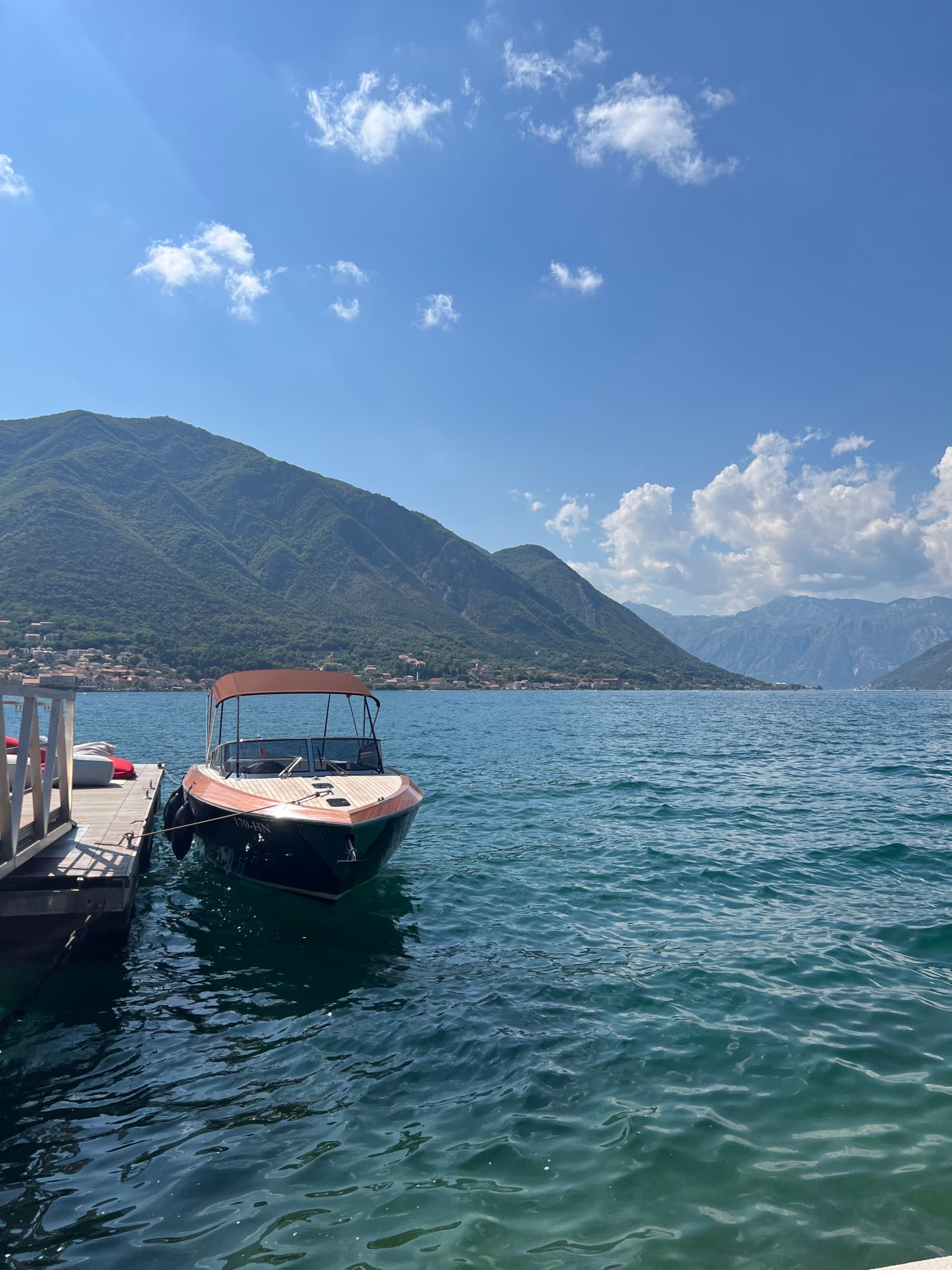 a boat floats in the bay surrounded by mountain range on a sunny day