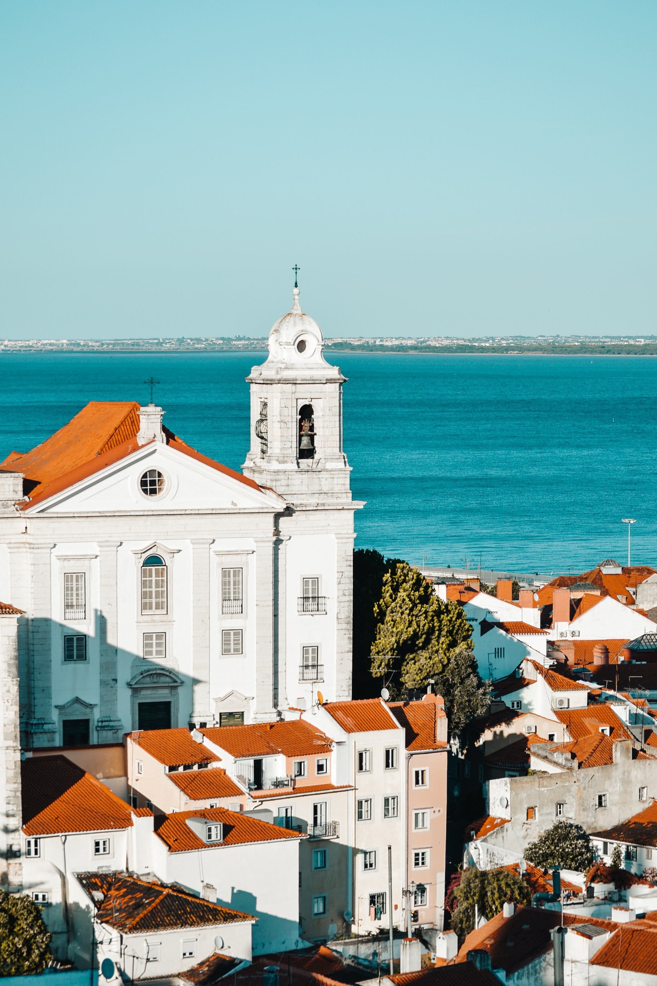 White and Orange Concrete Houses and Church Near Body of Water