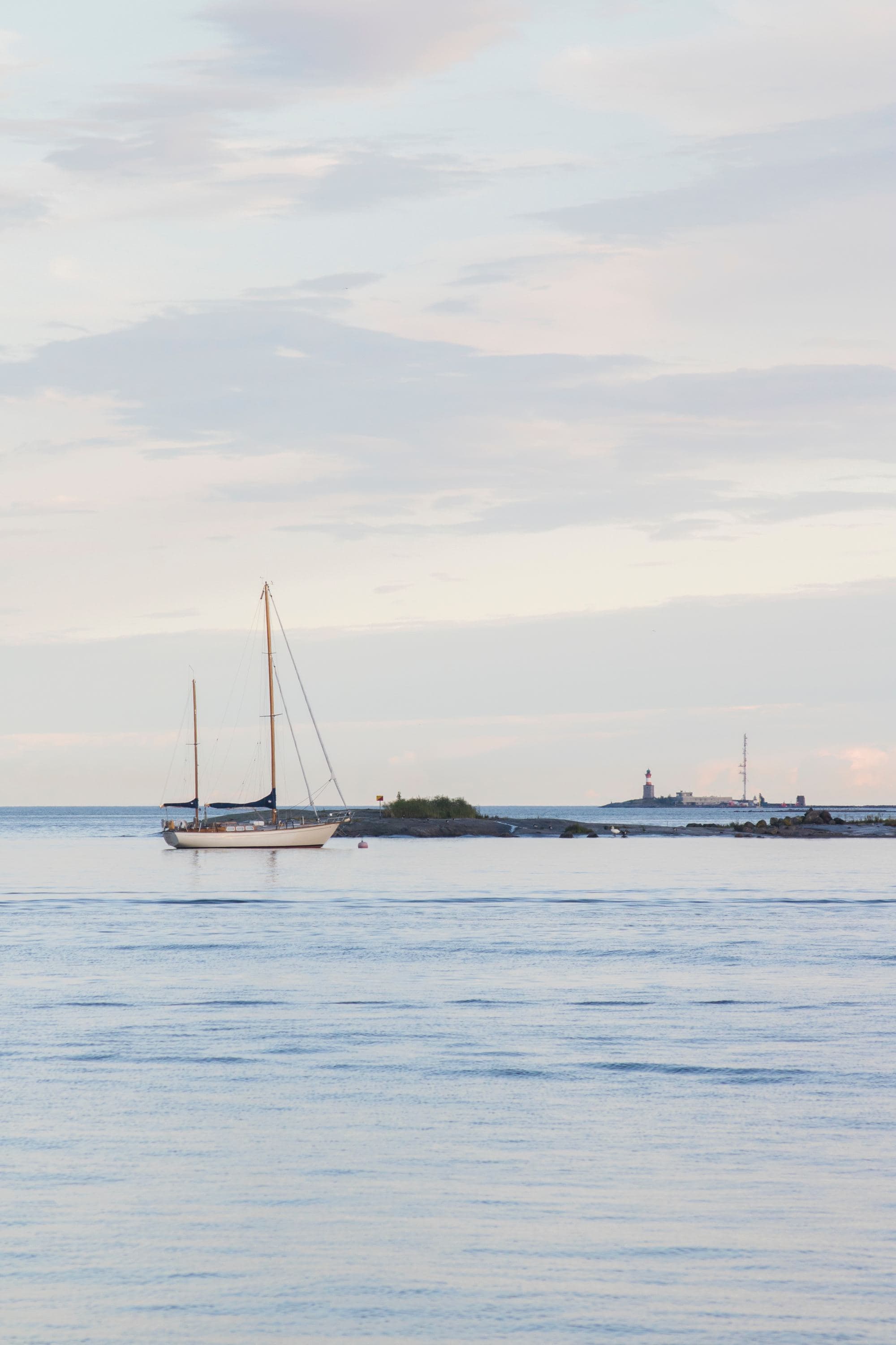 calm ocean at dusk with single moored sailboat