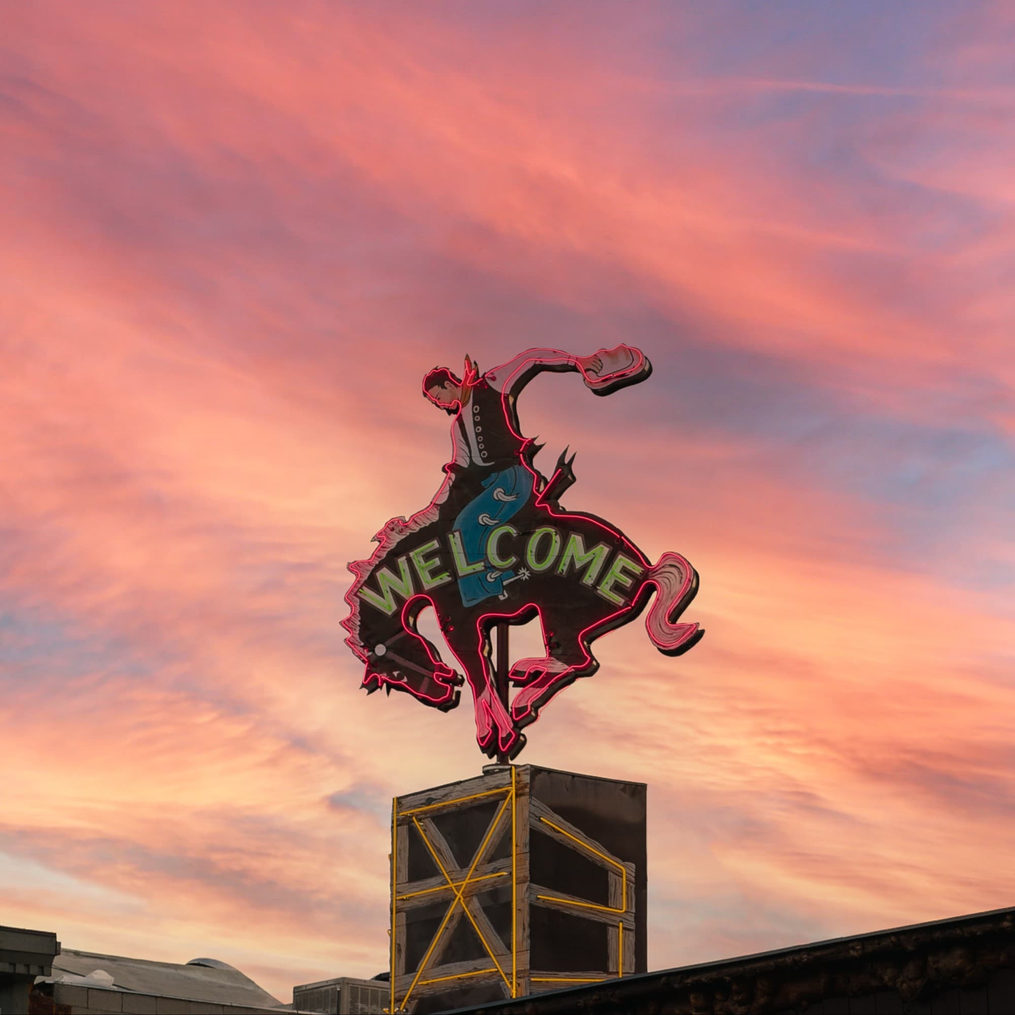 A sign on top of a hole of a man riding a horse saying, welcome,