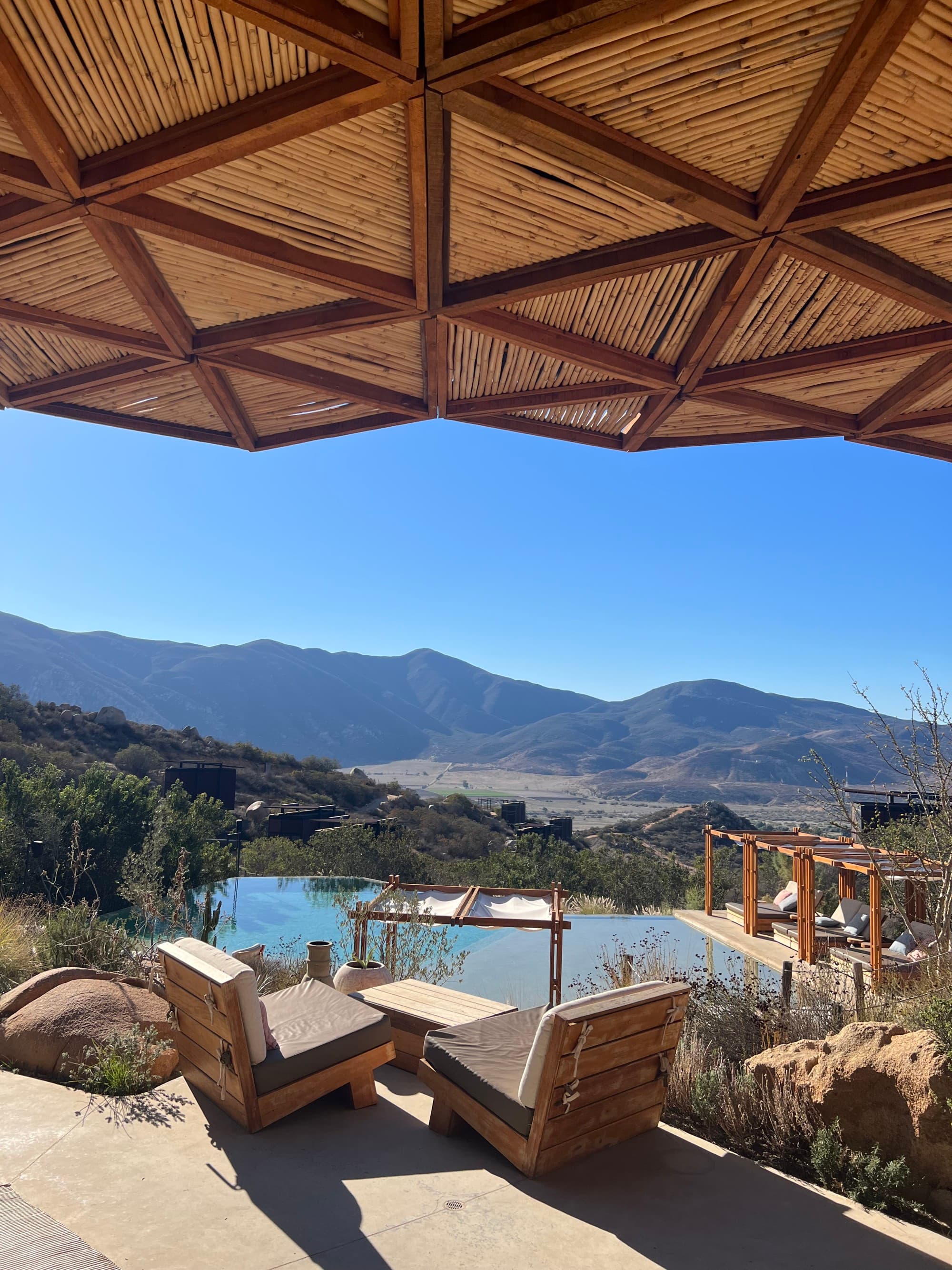 a pool of a resort hotel in a valley overlooking mountains on a clear blue day