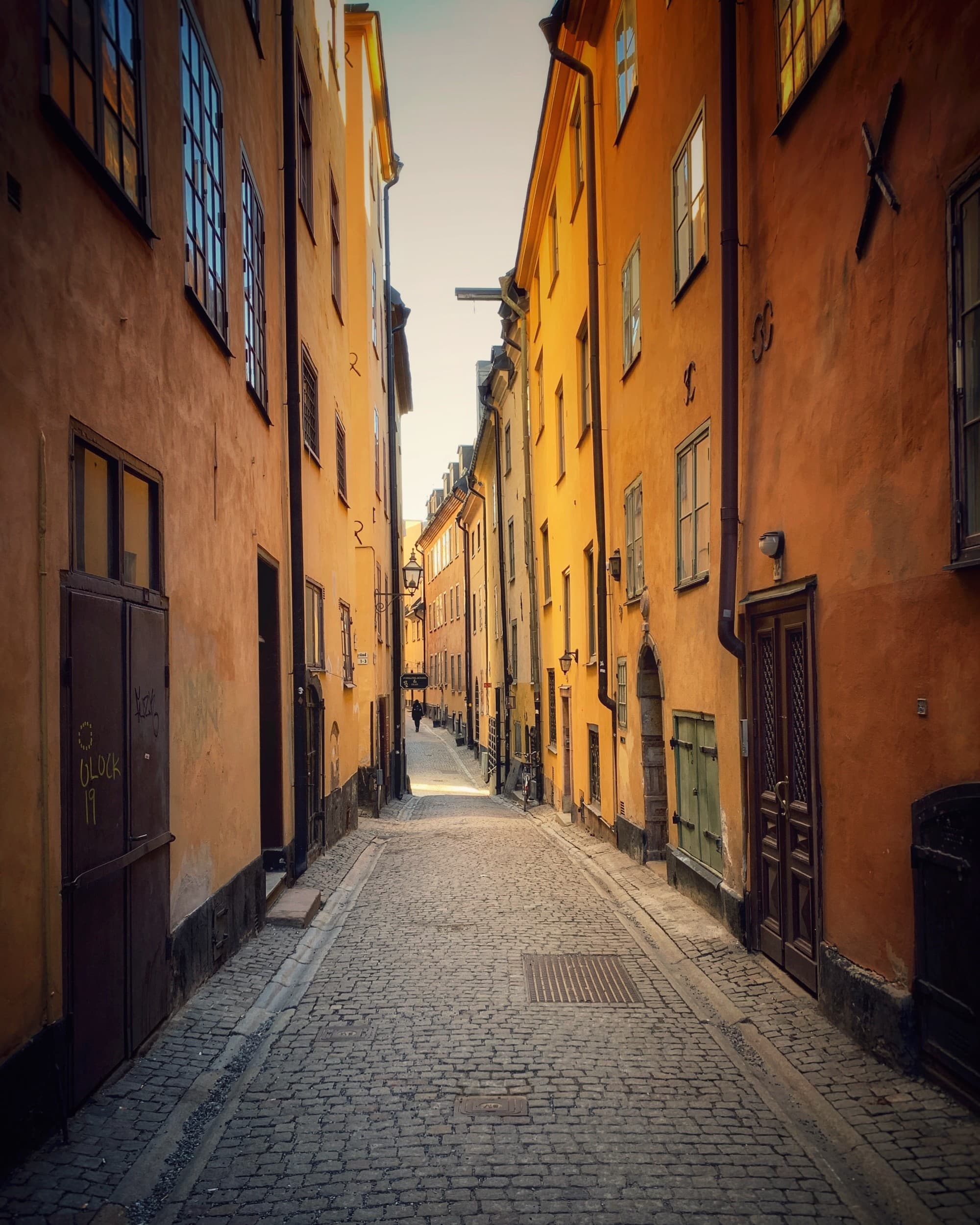 A narrow street between orange buildings.