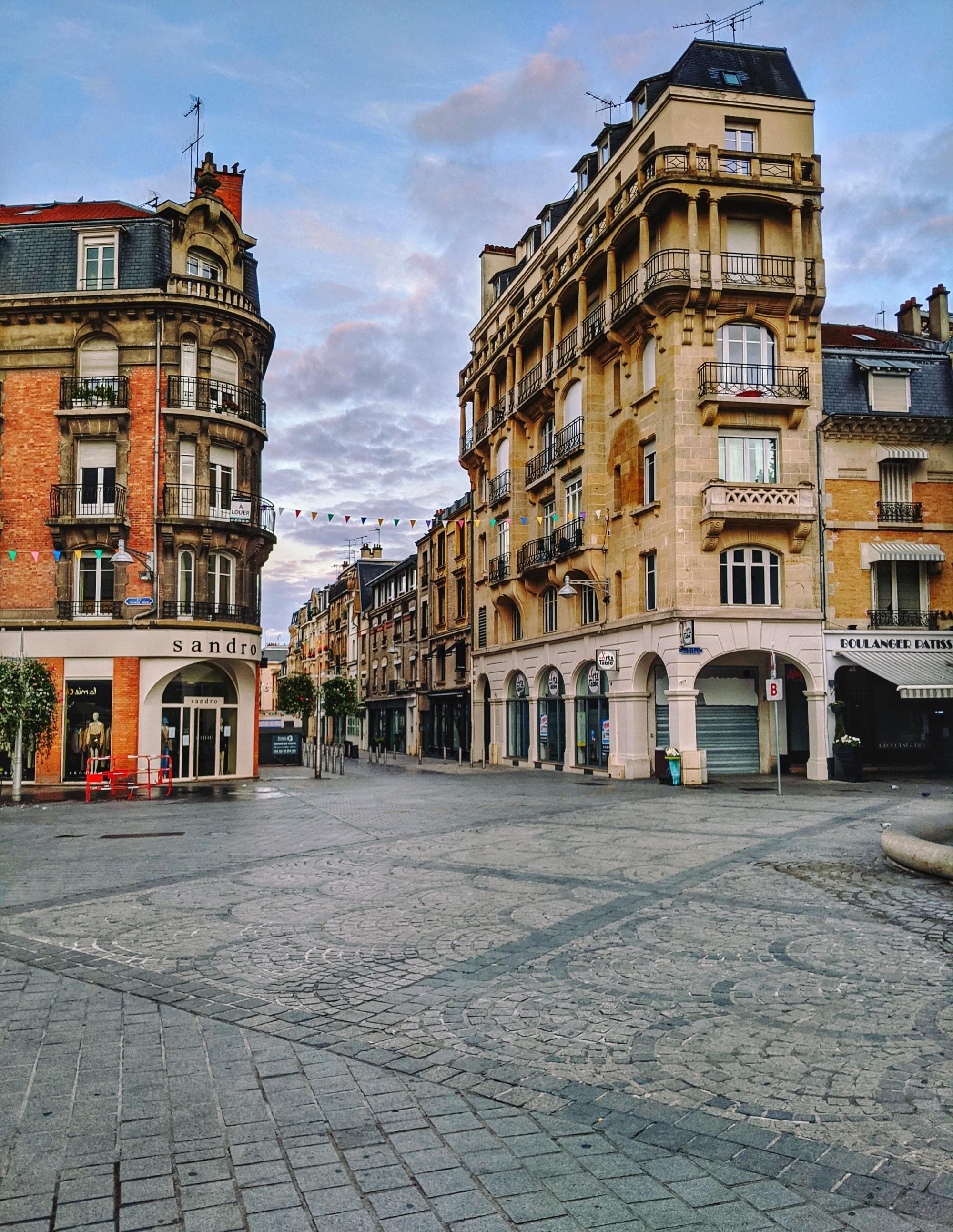 a cobblestone plaza leads to a street in a historic town in the afternoon