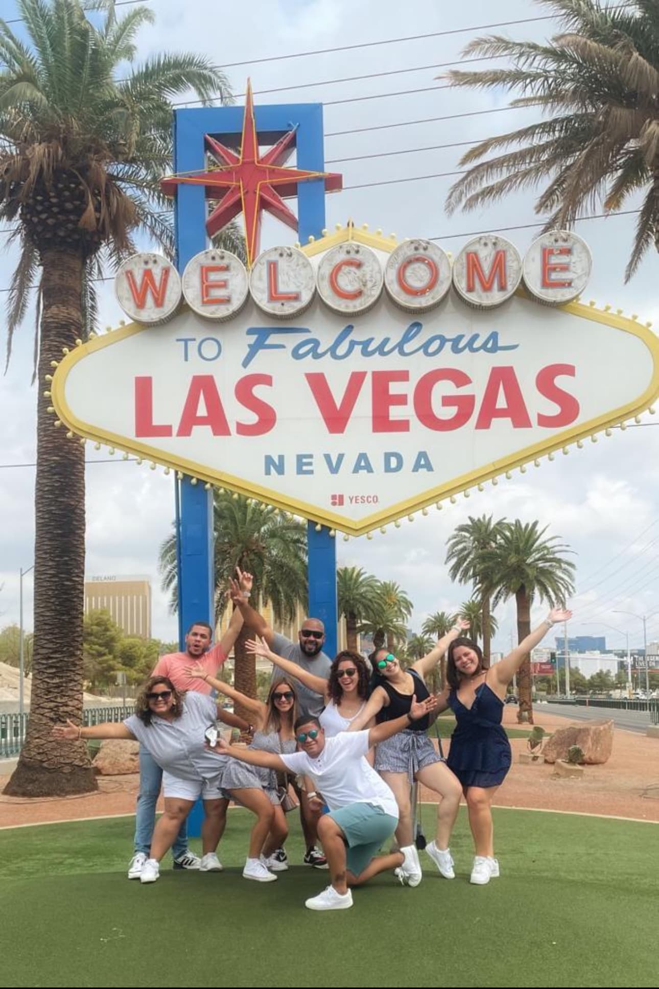 A group of people on front of Welcome to Fabulous Las Vegas board.