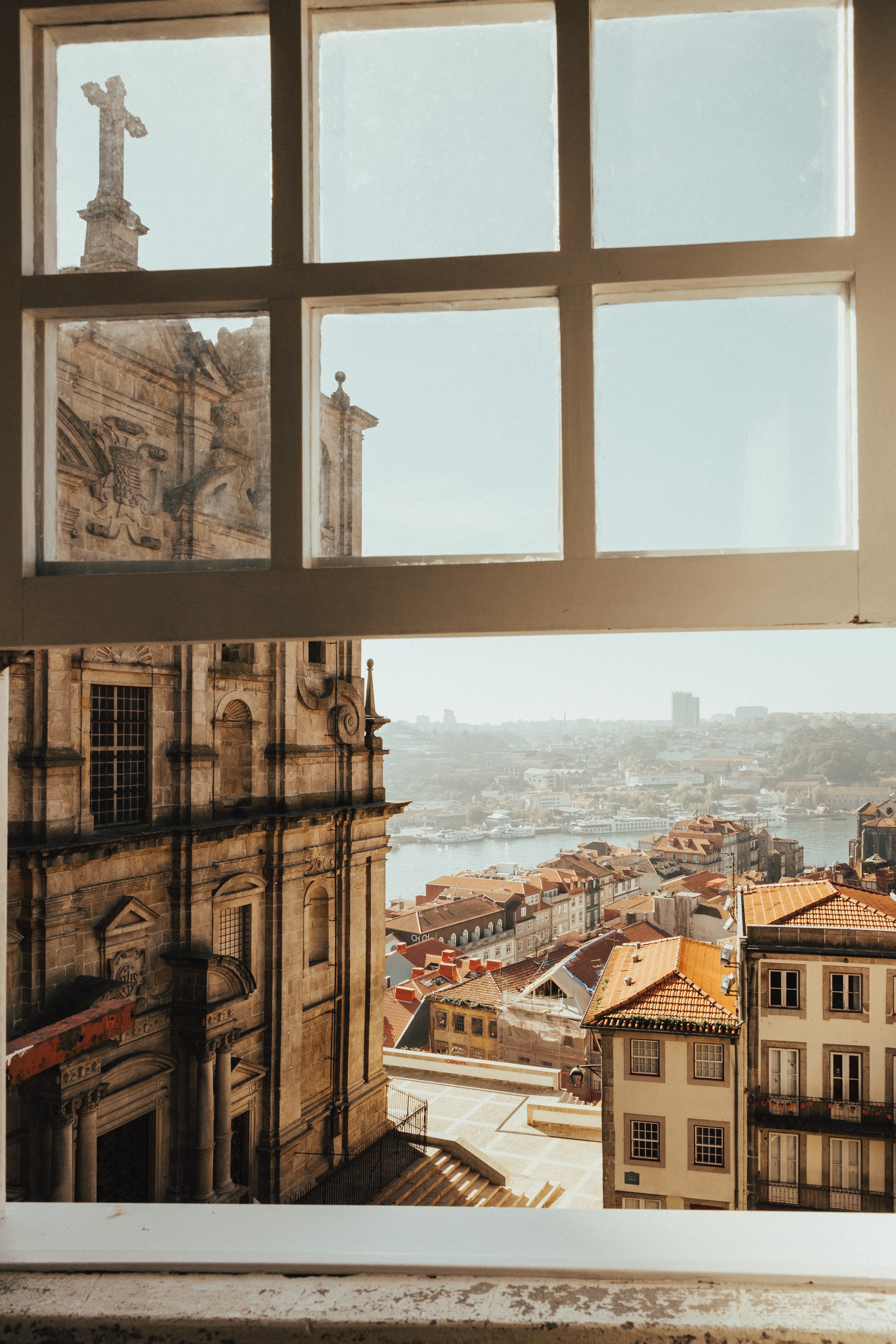 Window view of Porto featuring a street, church, ocean and local houses.