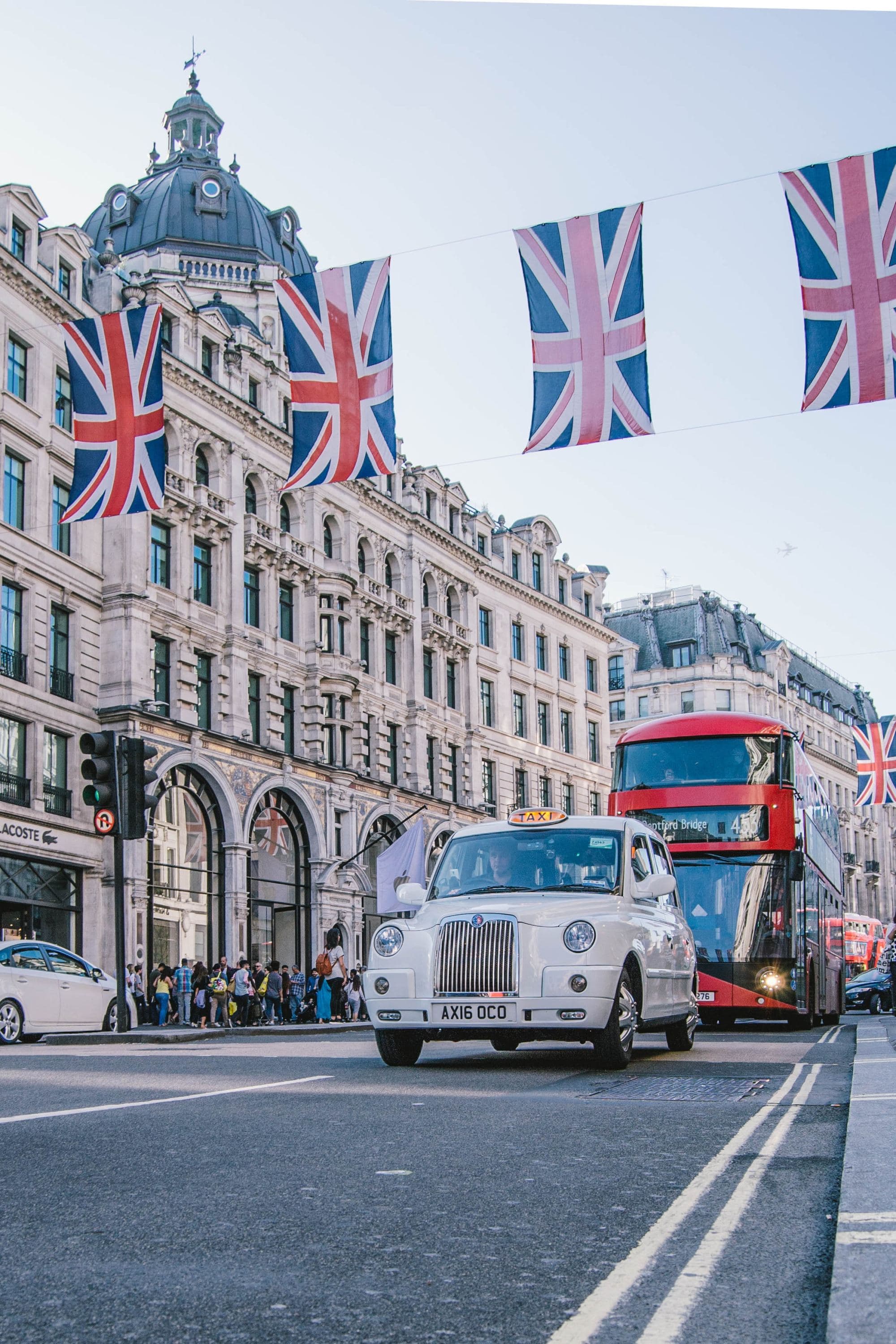 A photograph of a car and bus near a vintage building.