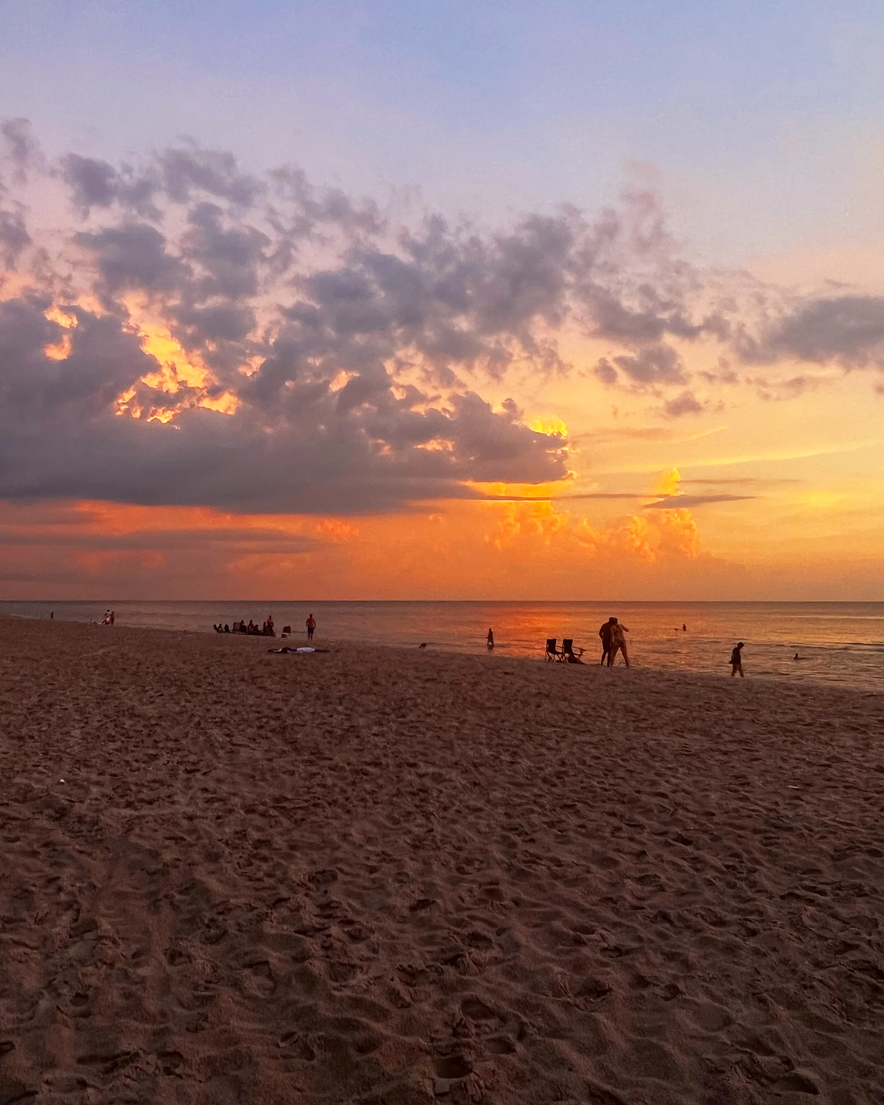 Sunset on the beach with people enjoying the view