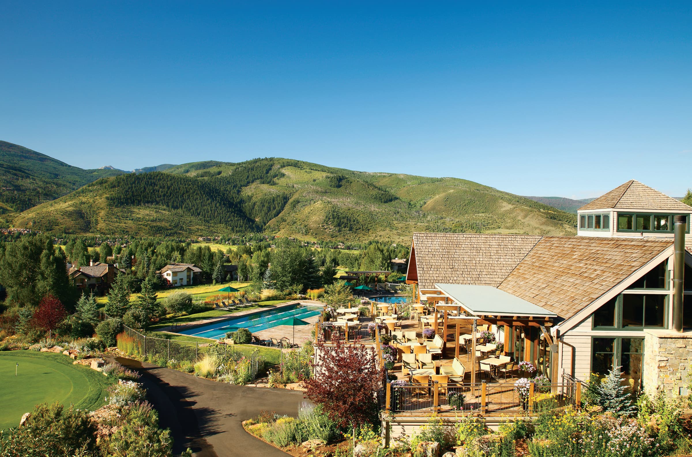 a building next to a pool with mountains in the background during daytime