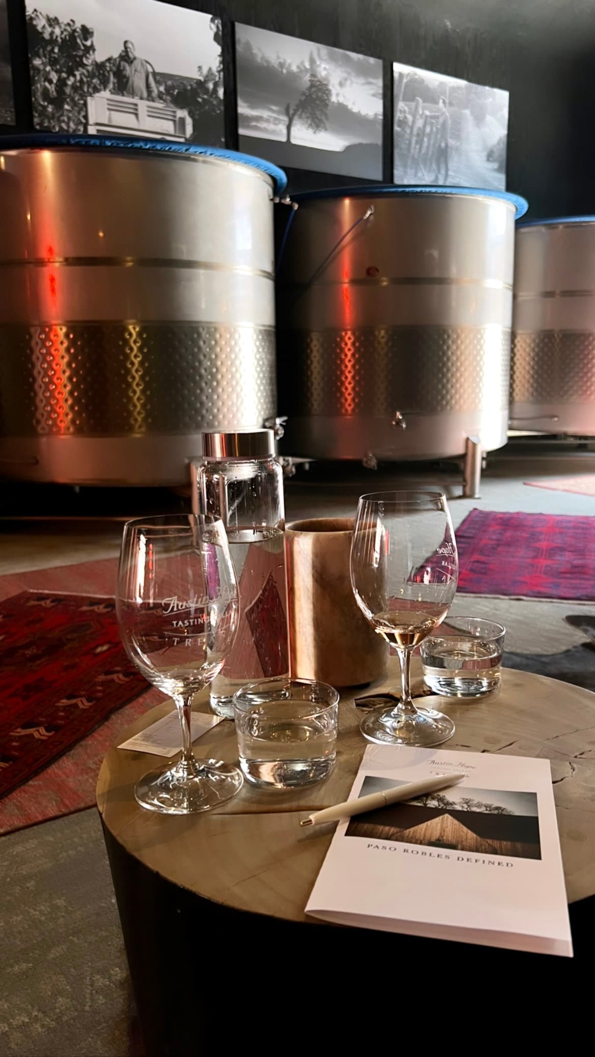 A small round table with empty wine glasses, pen and a brochure.