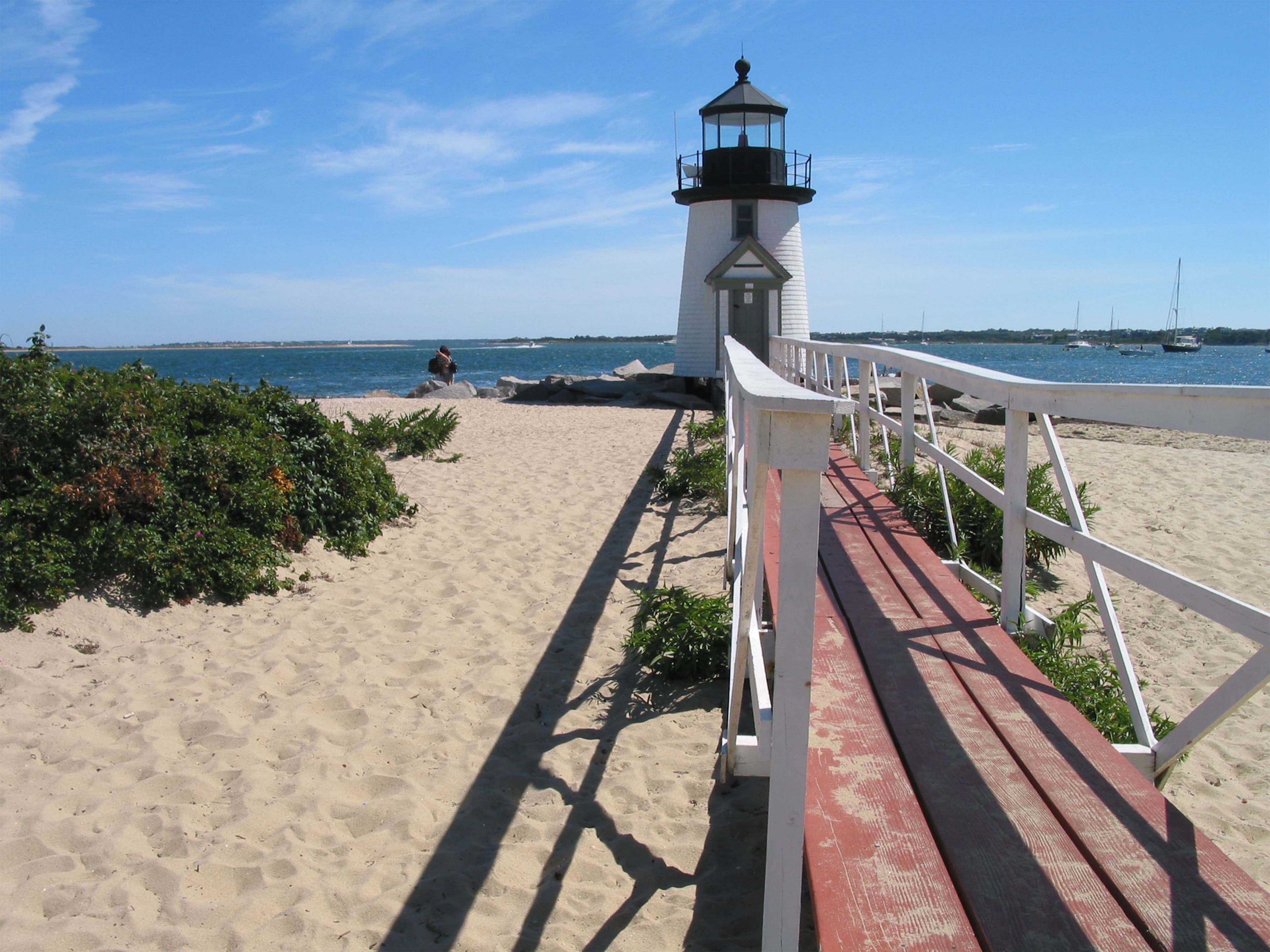 White and black lighthouse near a water body during daytime.