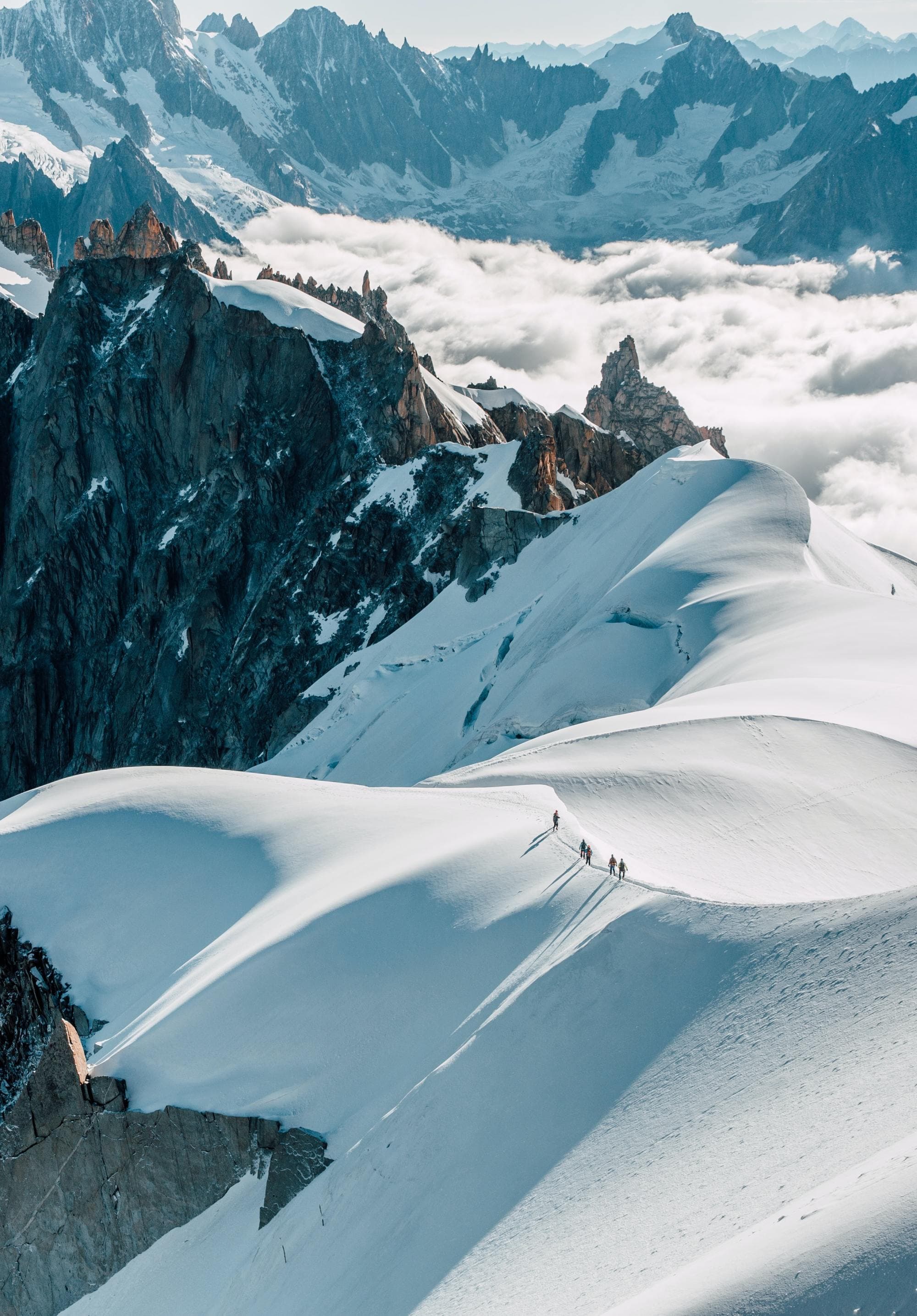 people hike through snowy cliffs