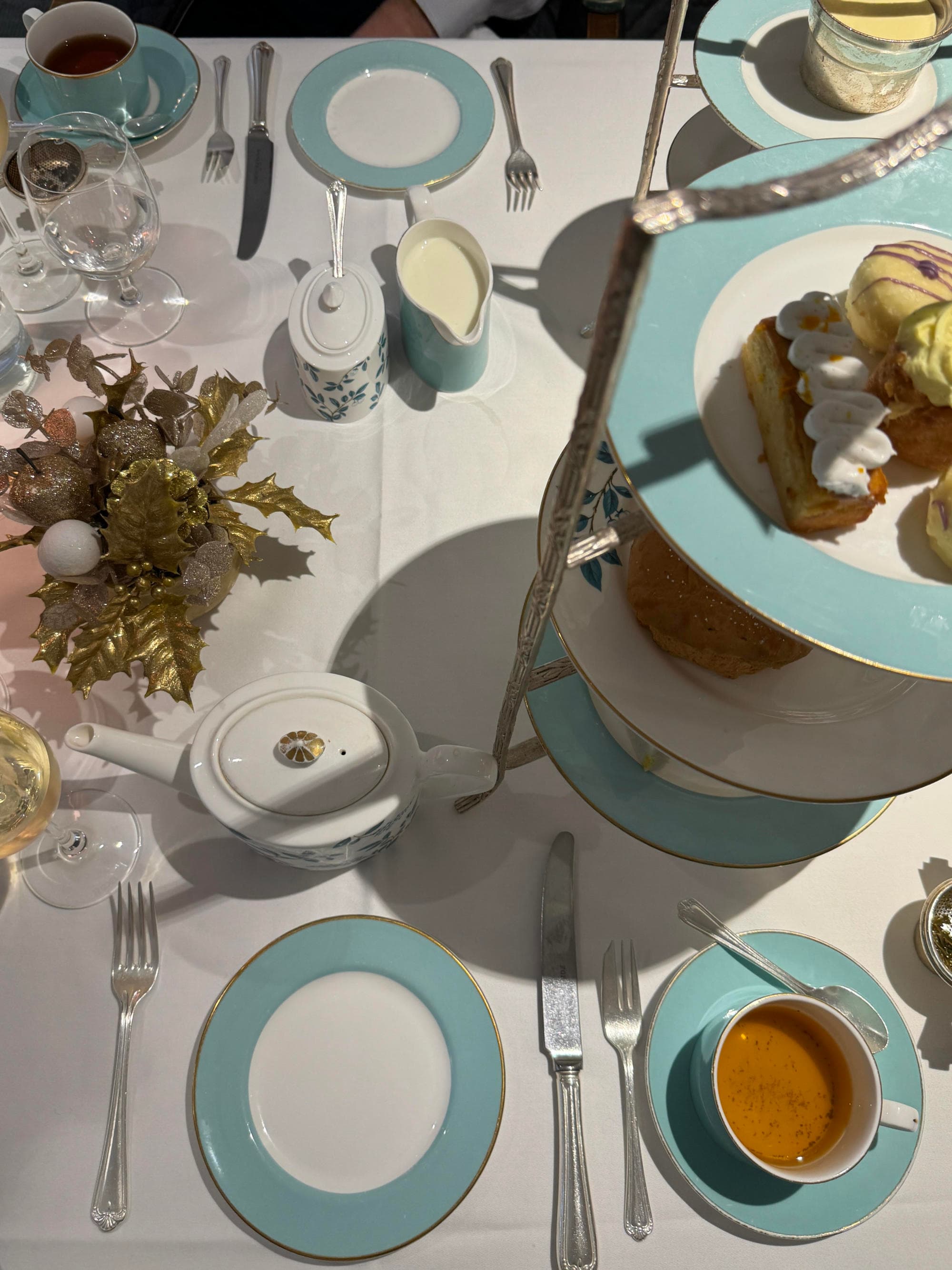 A birds-eye-view of blue and white plates on top of a white table cloth and center piece, designed for an afternoon of high-tea.