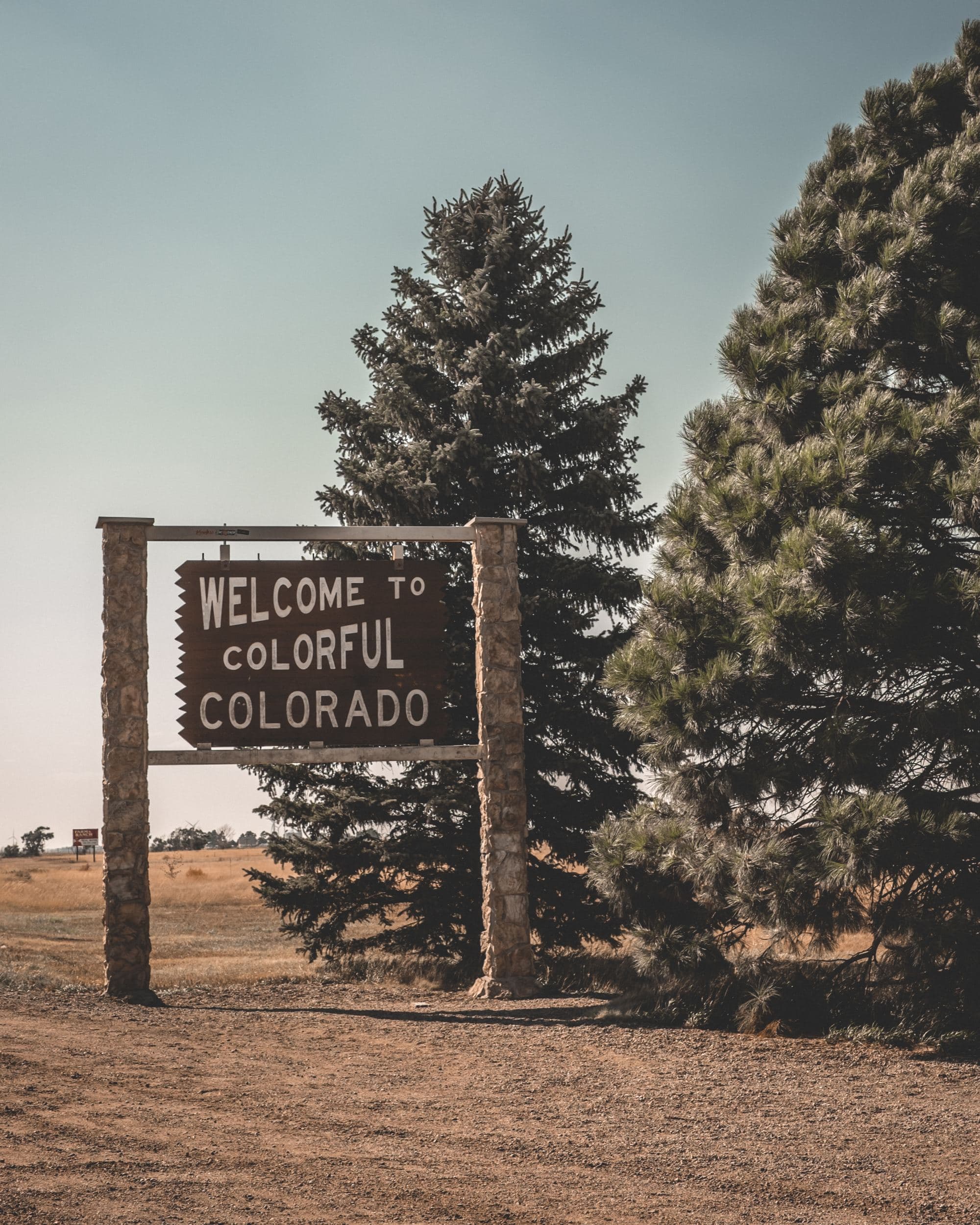 A picture of a wooden welcome sign that reads "Welcome to Colorful Colorado" during daytime.