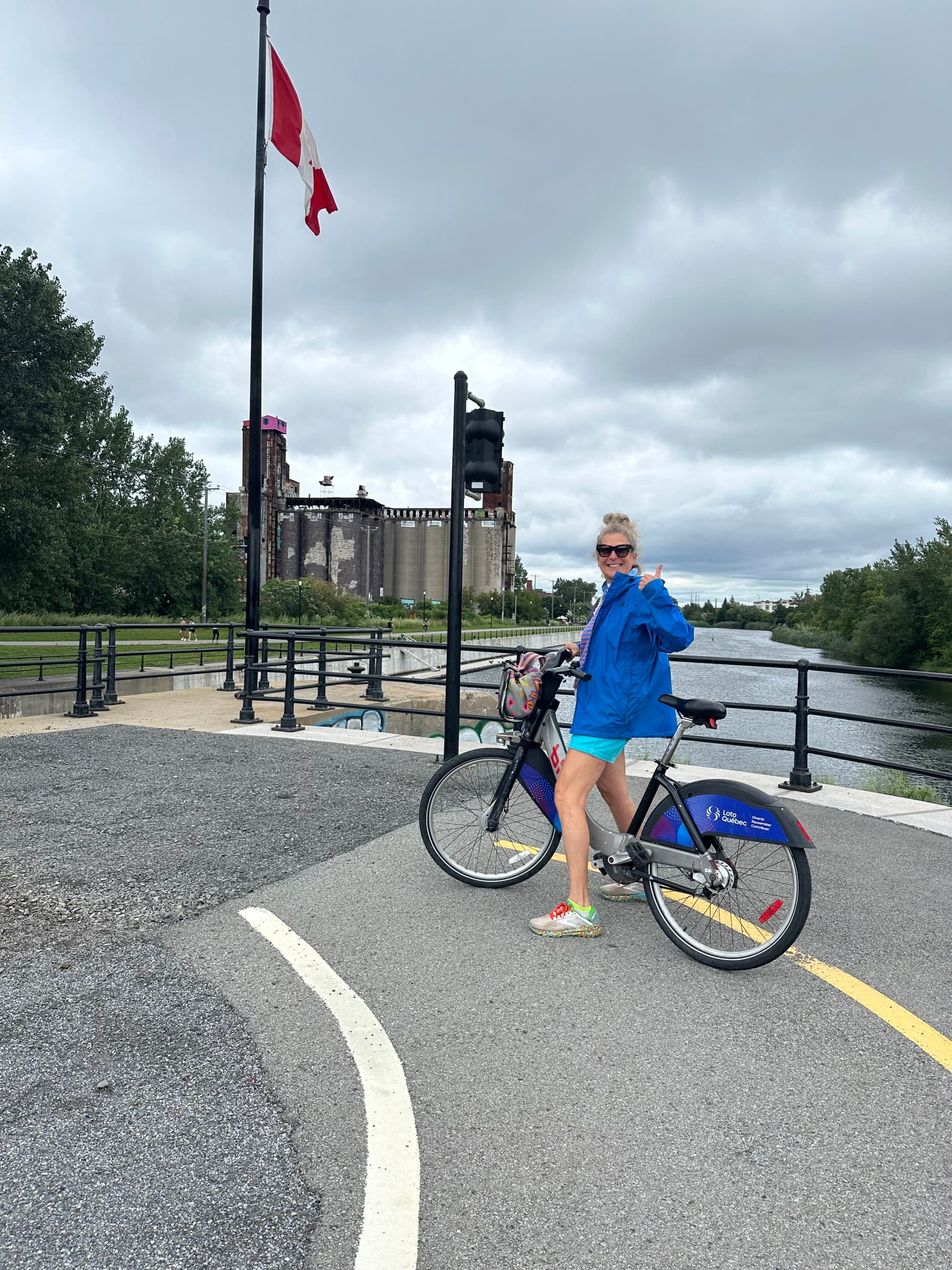 A girl posing on a bike near a Canadian flag at daytime.