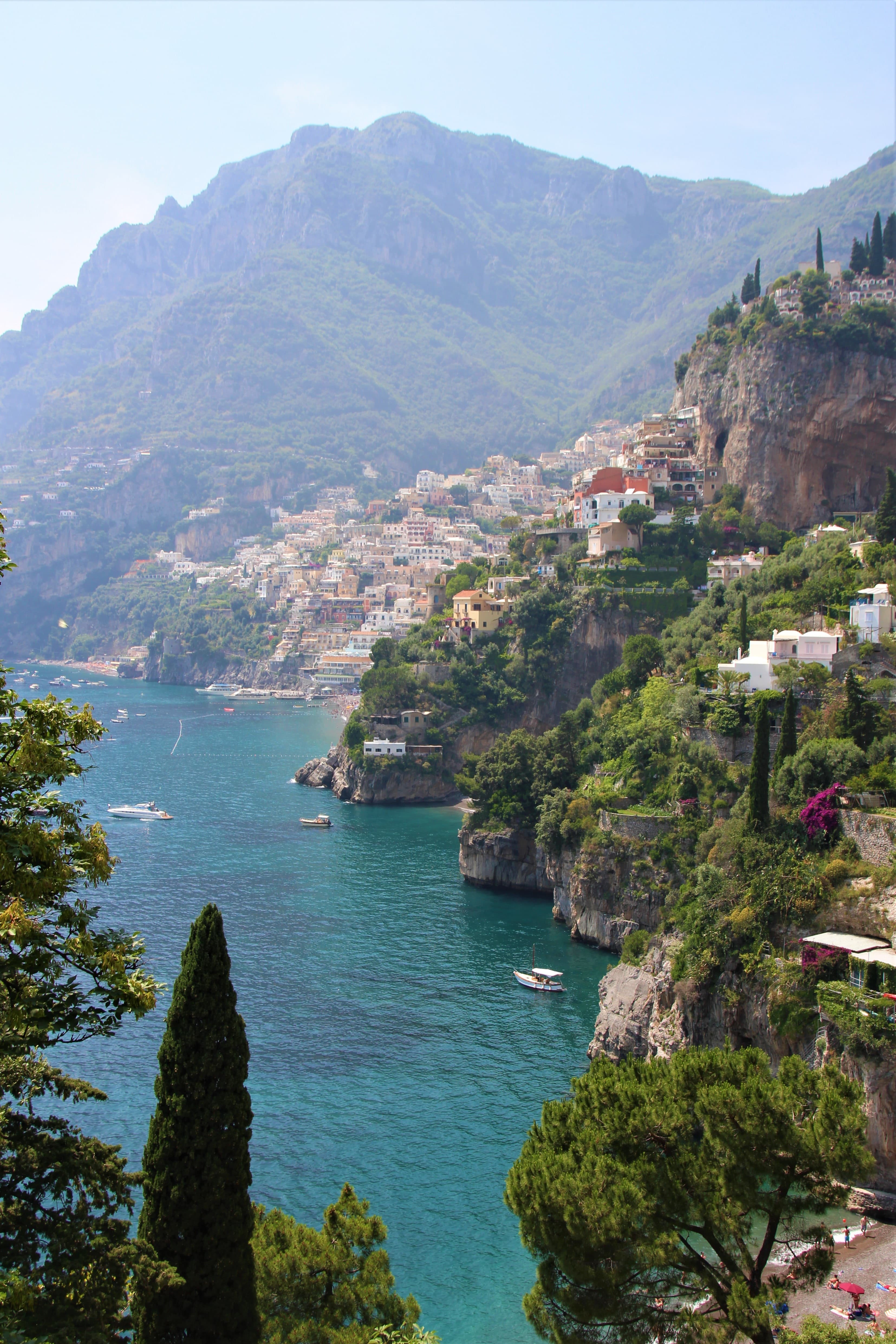 body of water next to cliff with houses during daytime