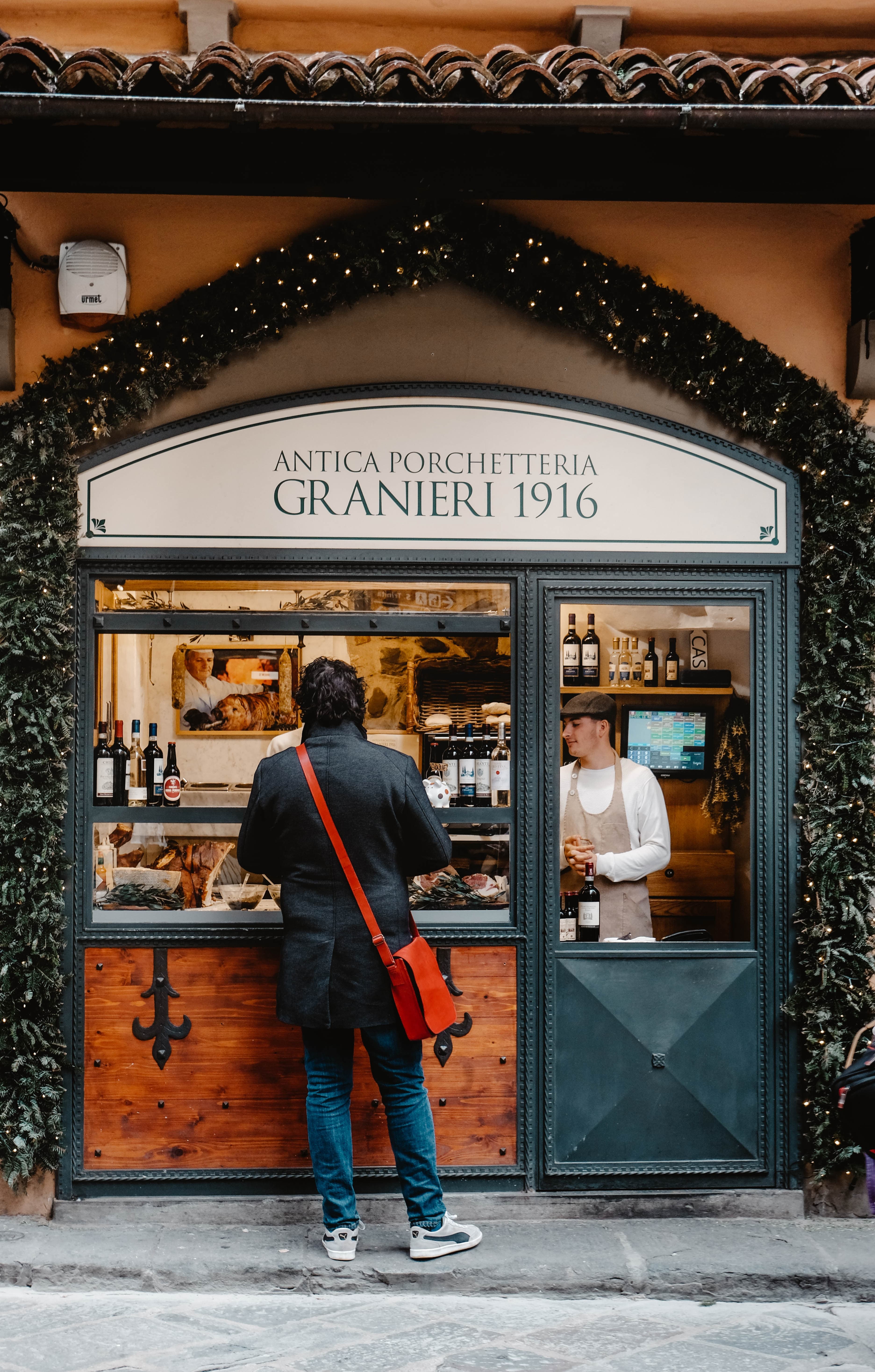 man standing outside of cafe during daytime