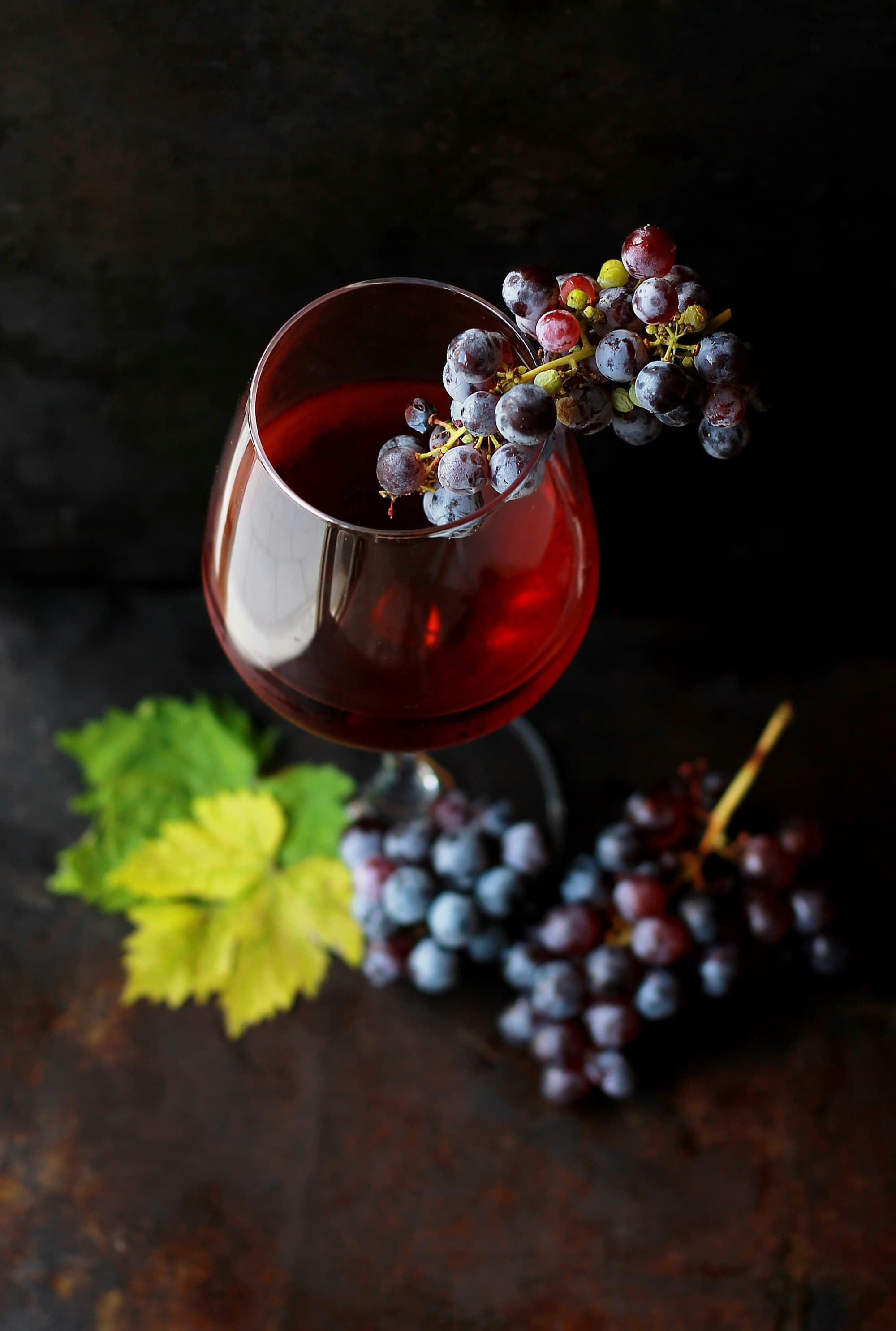 A picture of a wine glass with black grapes.