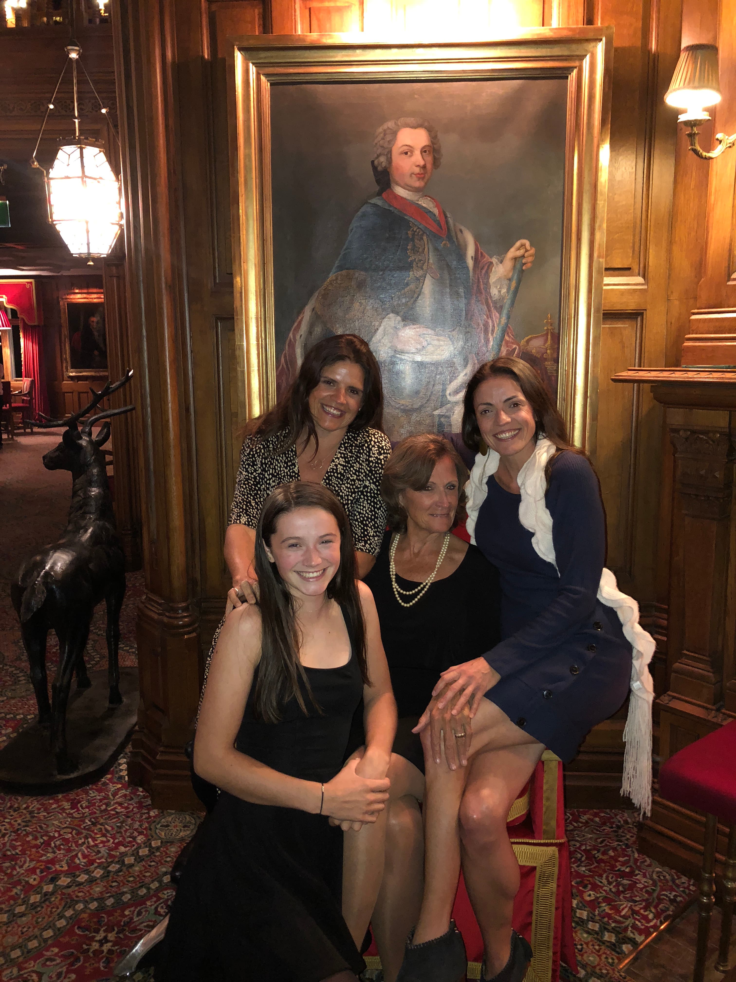 A group of women posing in front of a painting