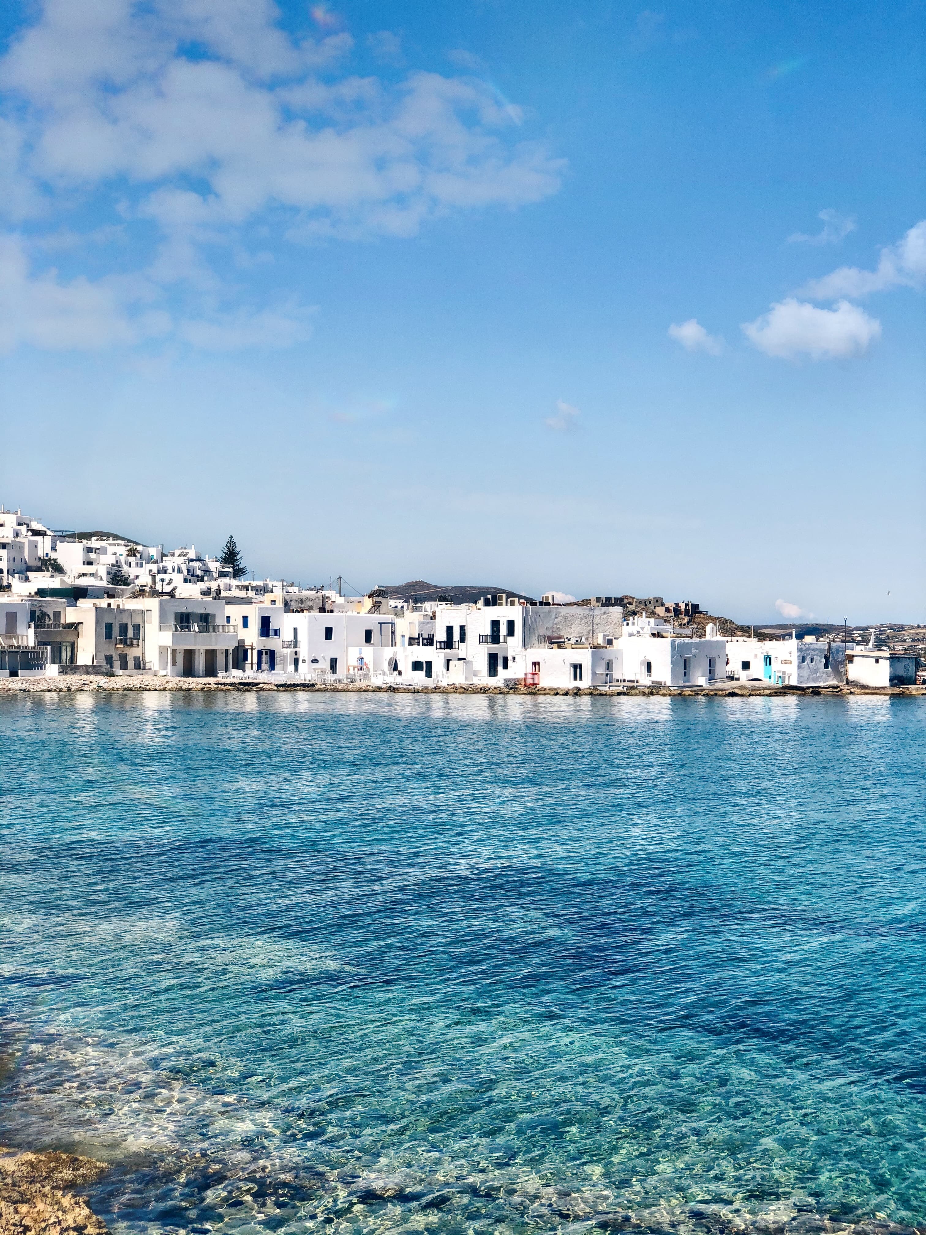 The views of a whitewashed Greek city from water.