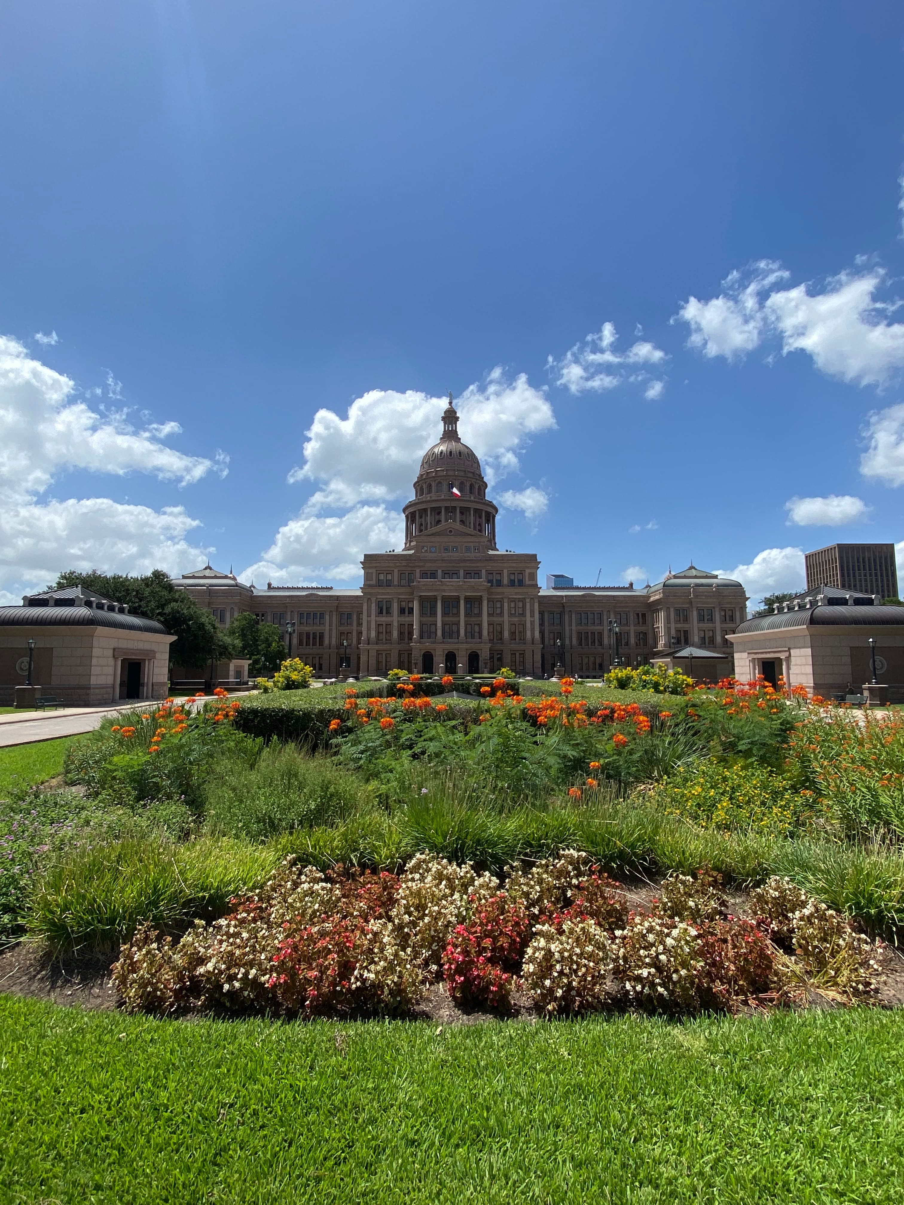 The Texas State Capitol at Austin, Texas reaches to the sky on sunny day dotted with clouds.