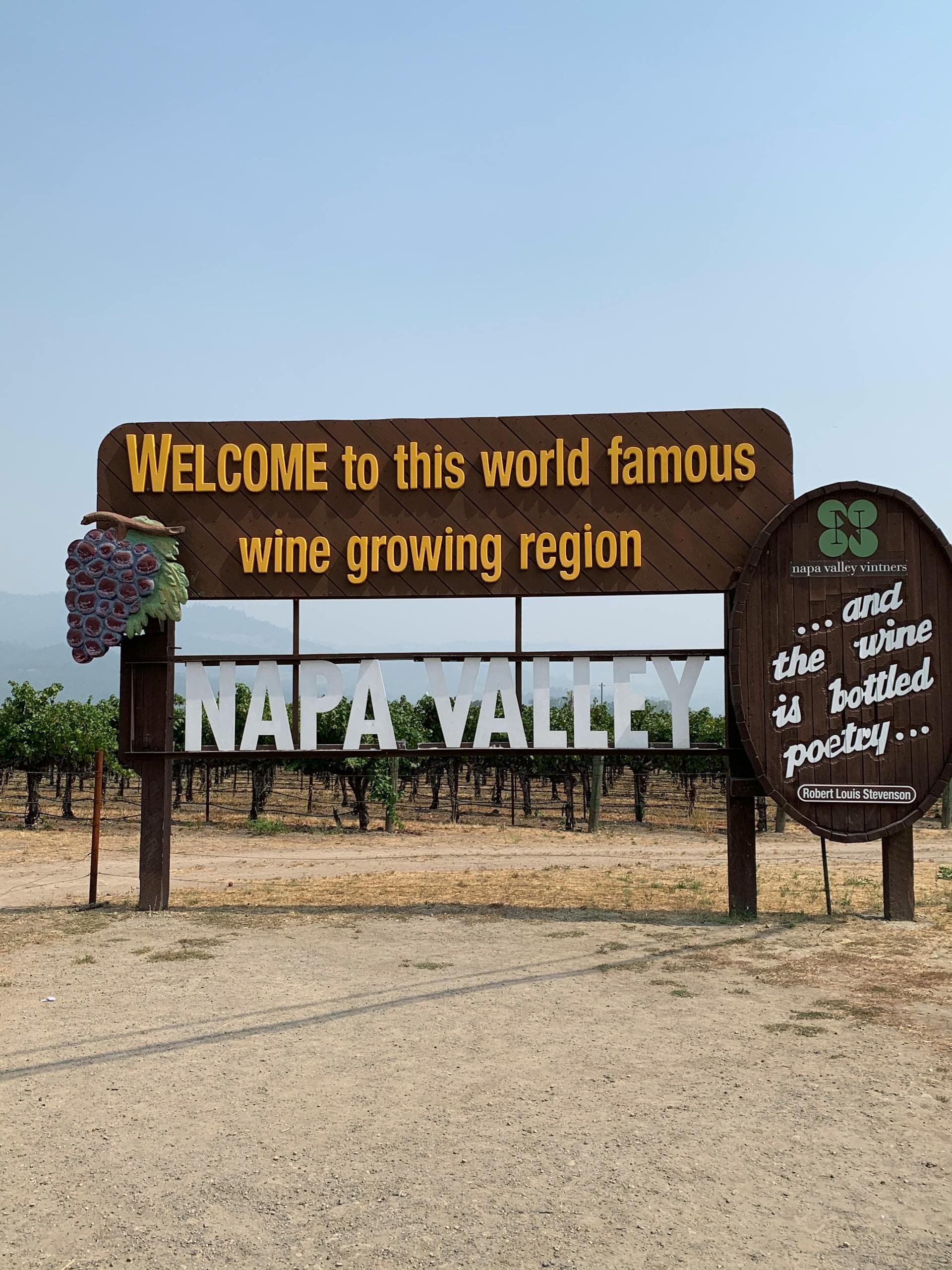 Welcome signage upon entering Napa Valley with vines in the background on a sunny day.