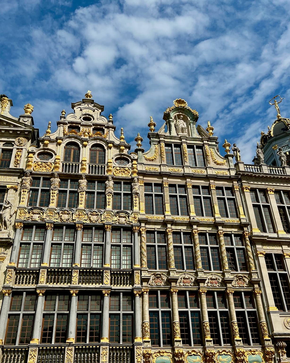 The architecture of Grand Palace stunningly reaches to the sky on a clear day dotted with clouds.