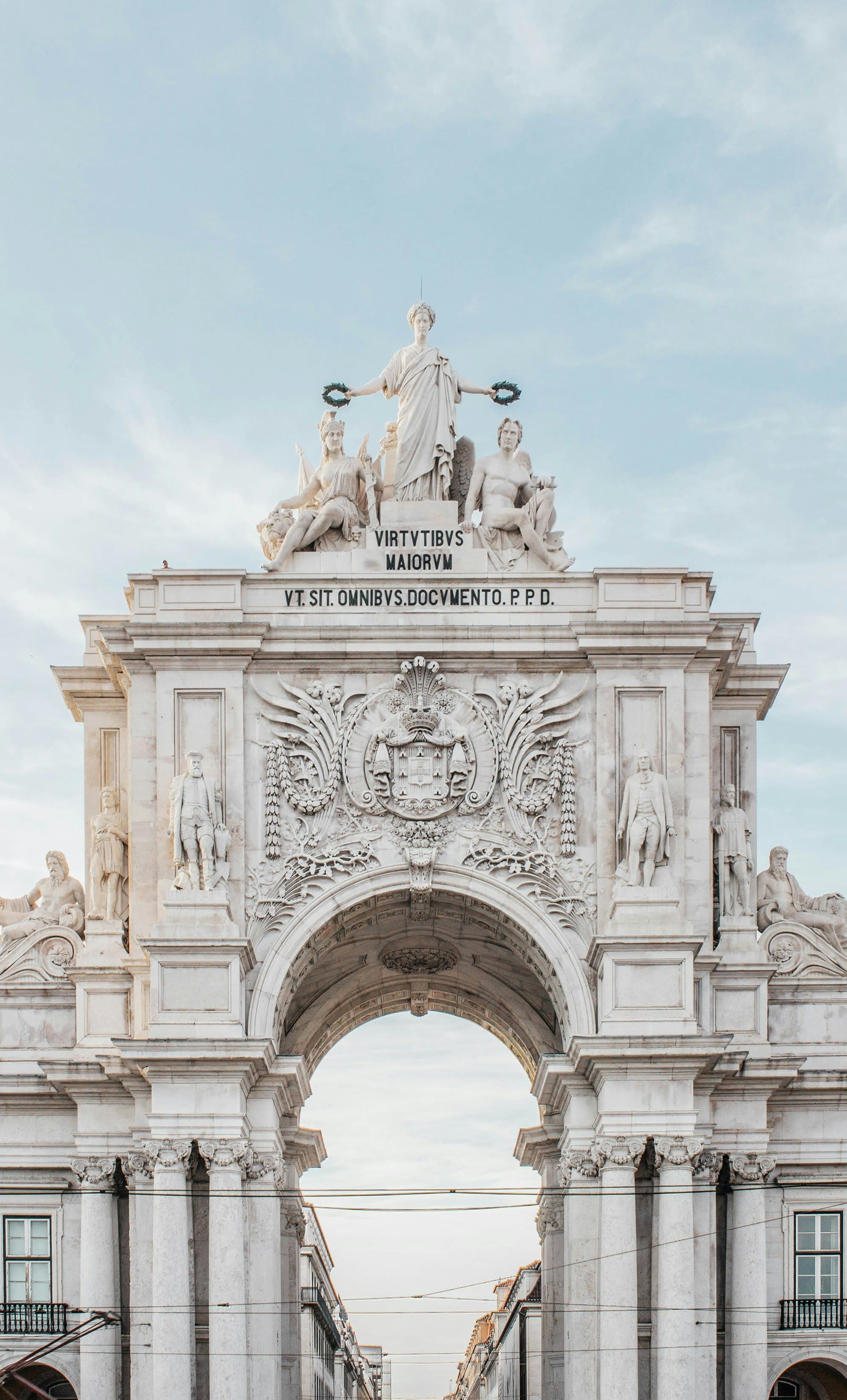 An ornate stone archway with Latin inscriptions and sculptures under a clear sky.