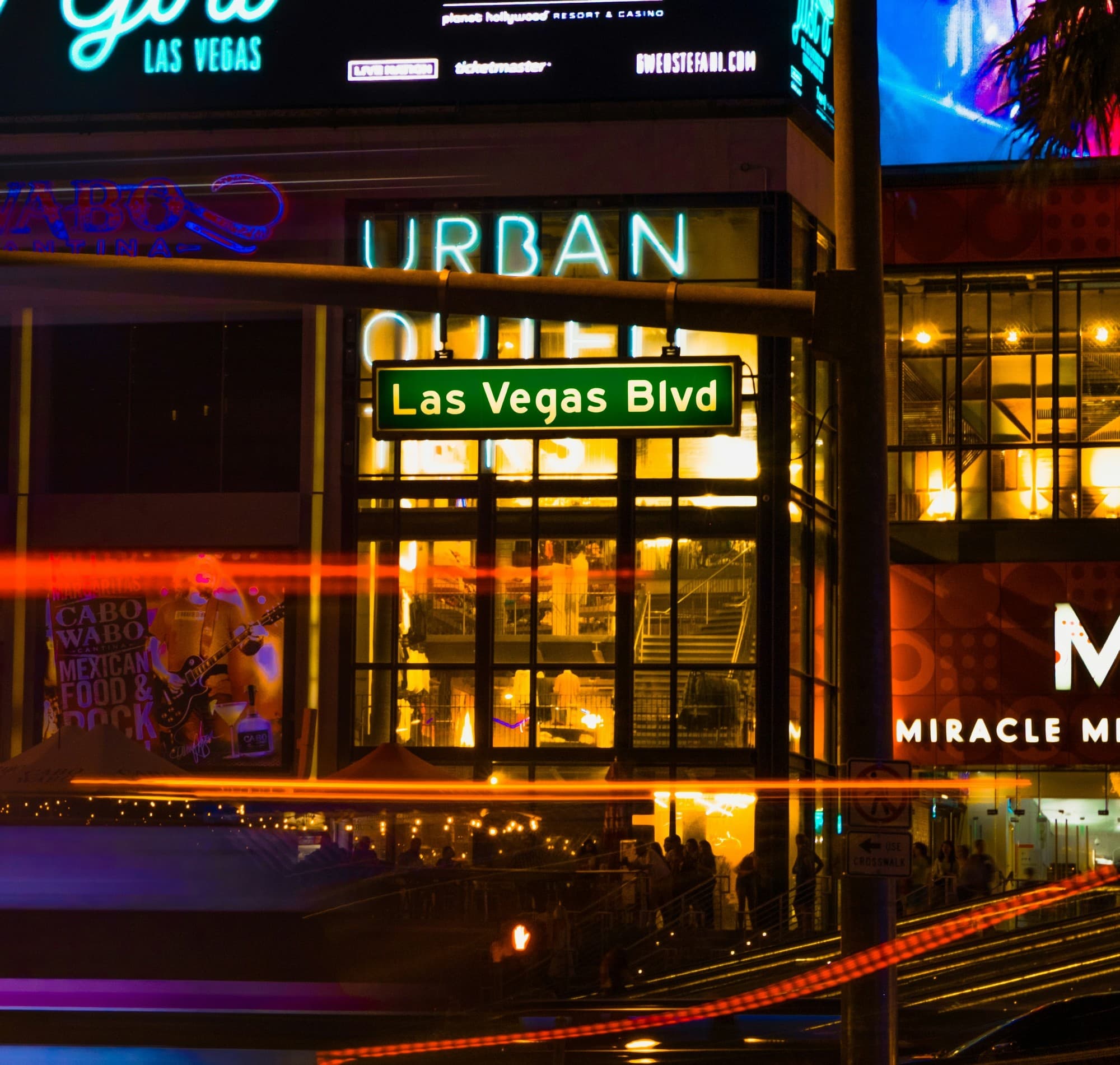 Street sign that reads "Las Vegas Blvd on a street with buildings and neon signs at night.