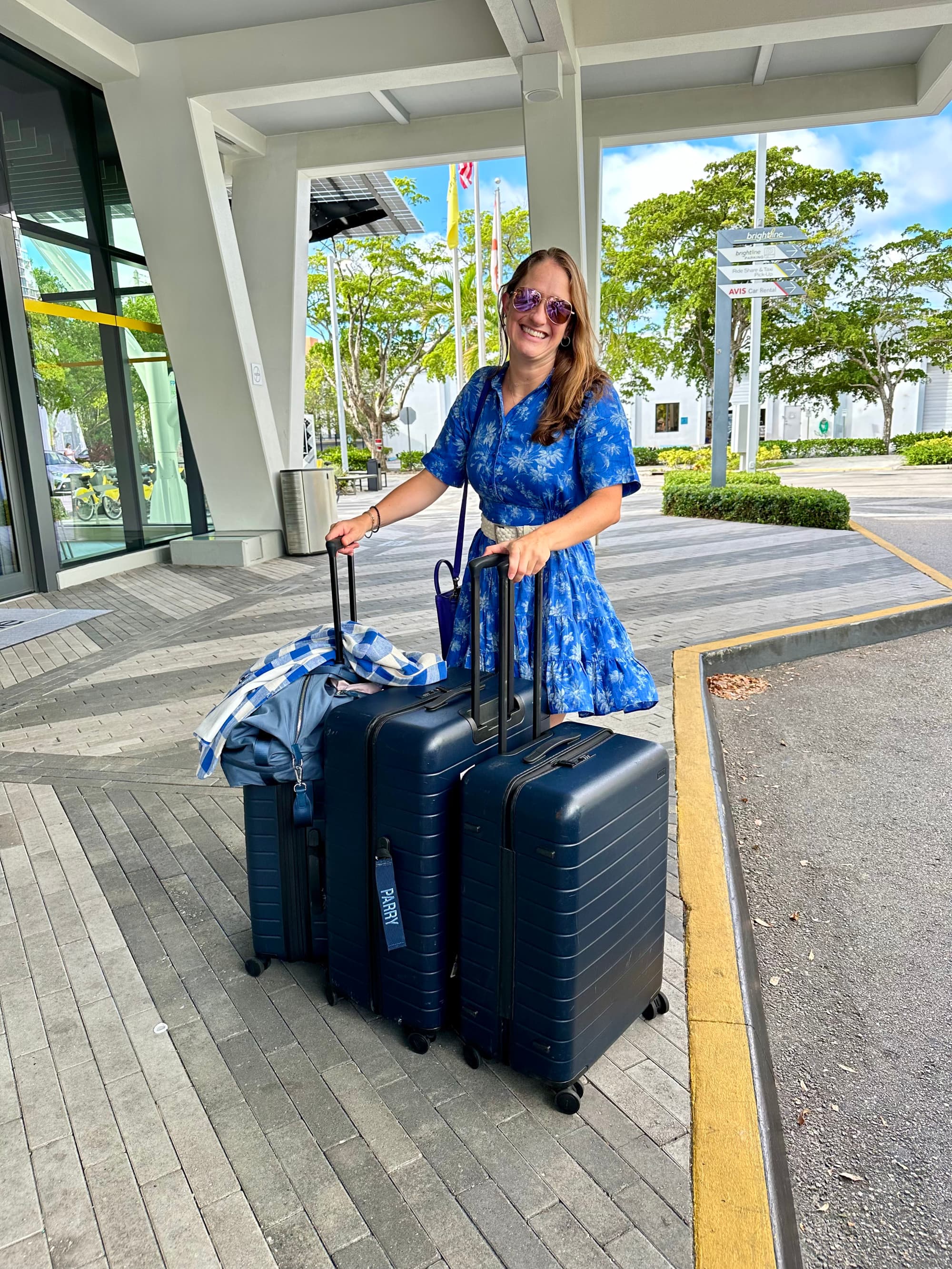 A woman standing with three suitcases.