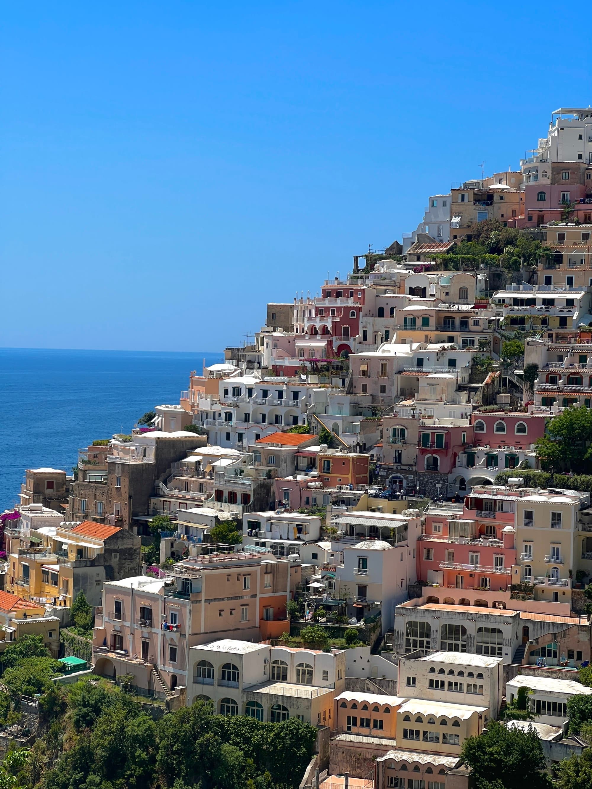 Colorful buildings on a maintain with sea in the background.