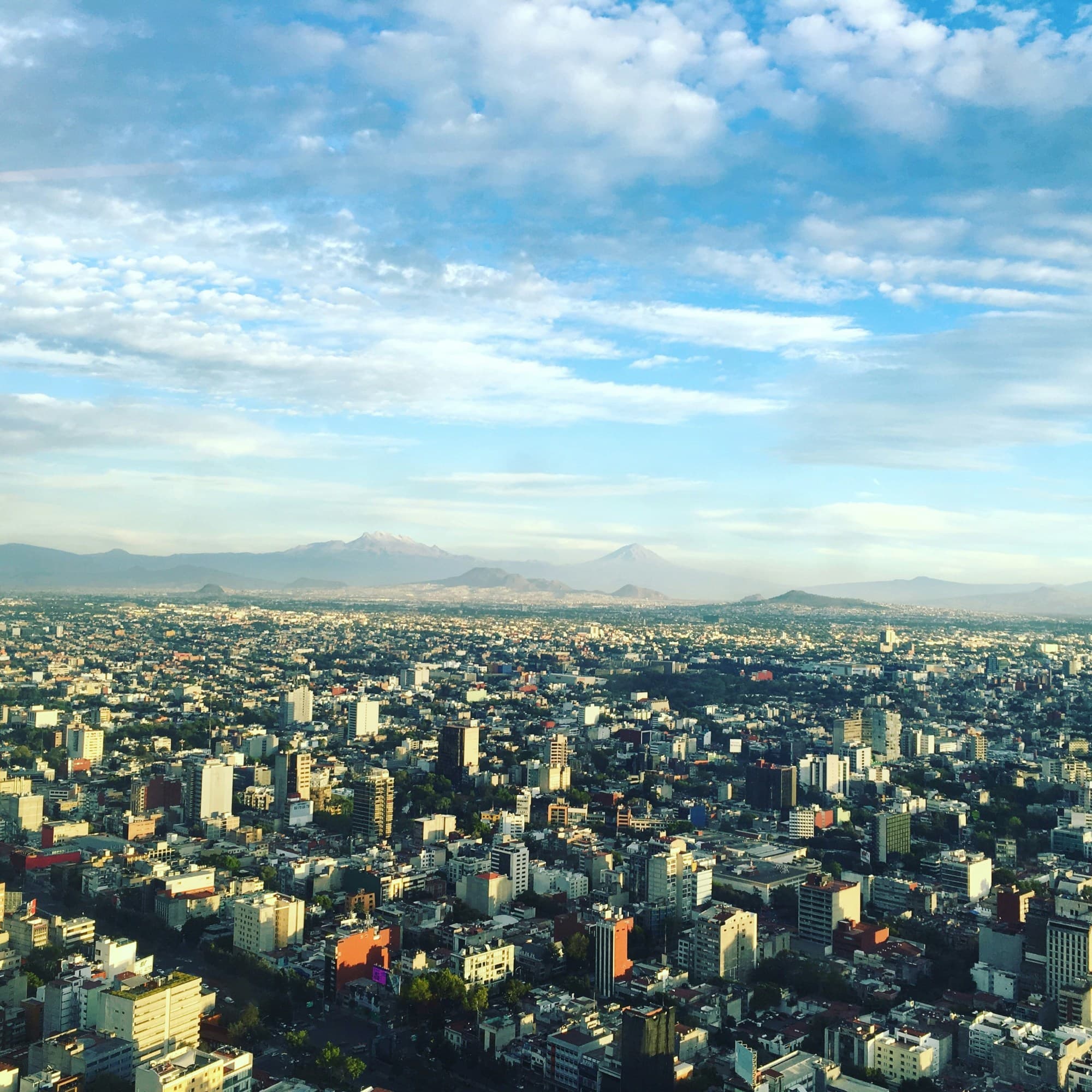 Aerial view of city with buildings and mountains at background.