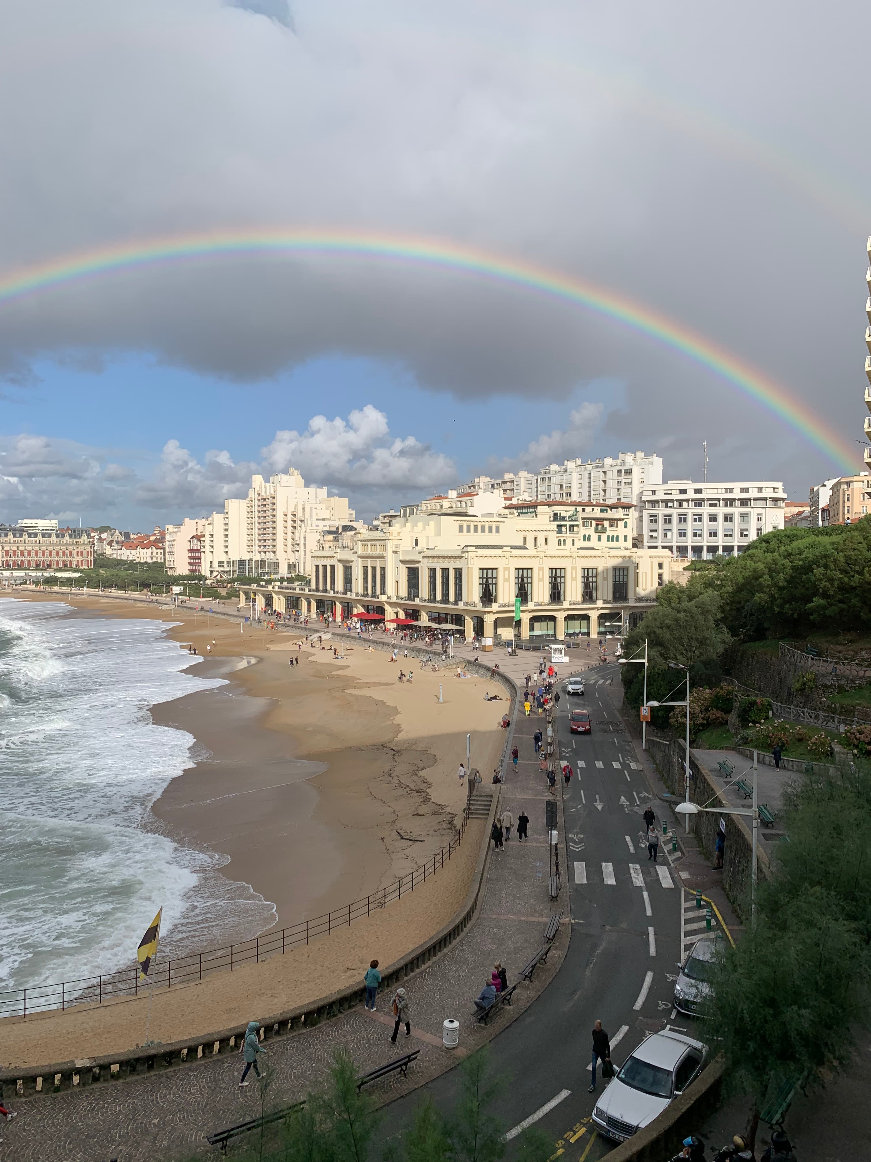 A rainbow over the Biarritz coastline with white buildings in the background.