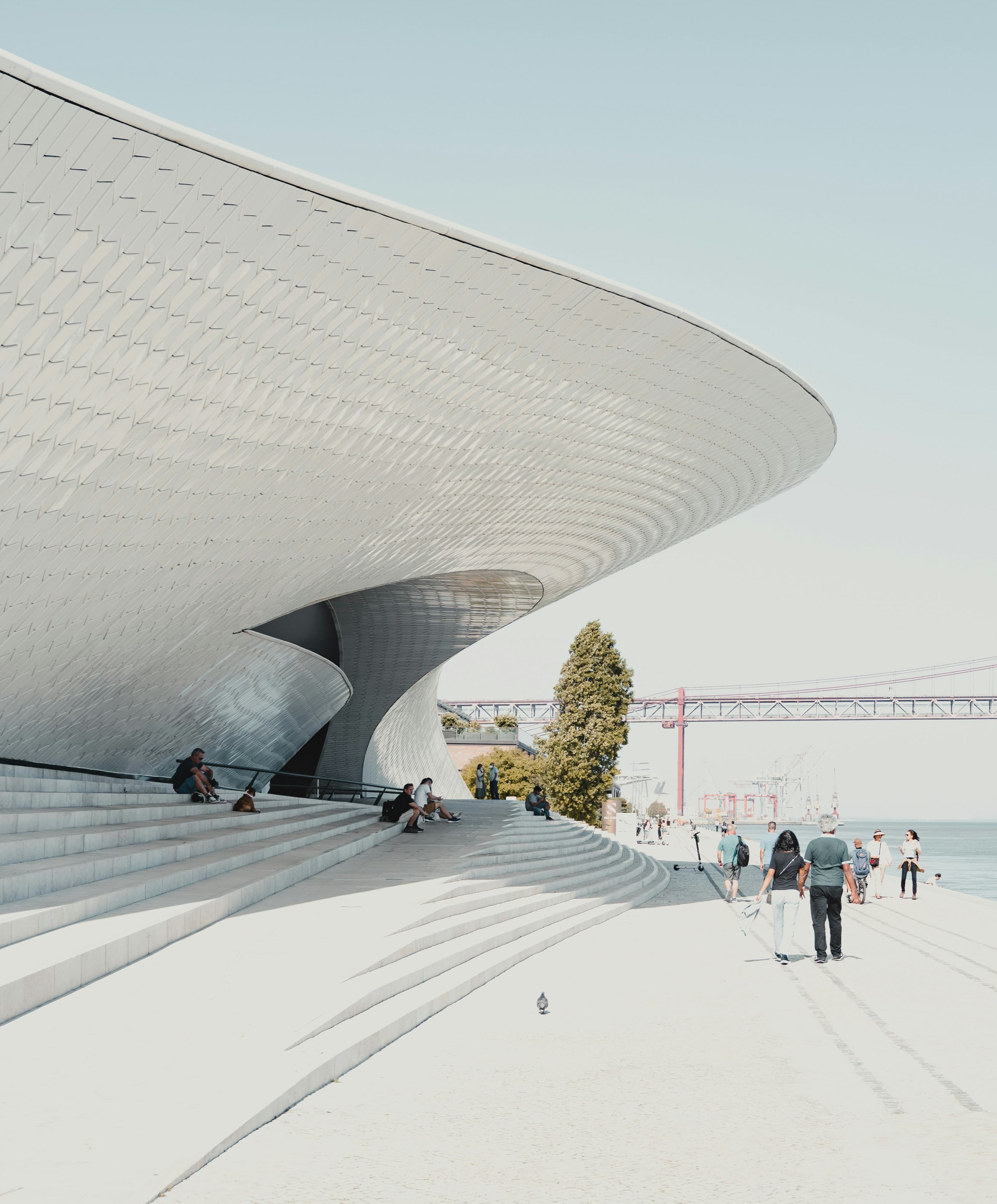 A modern architectural marvel, the building features a striking wavy roof by the water.