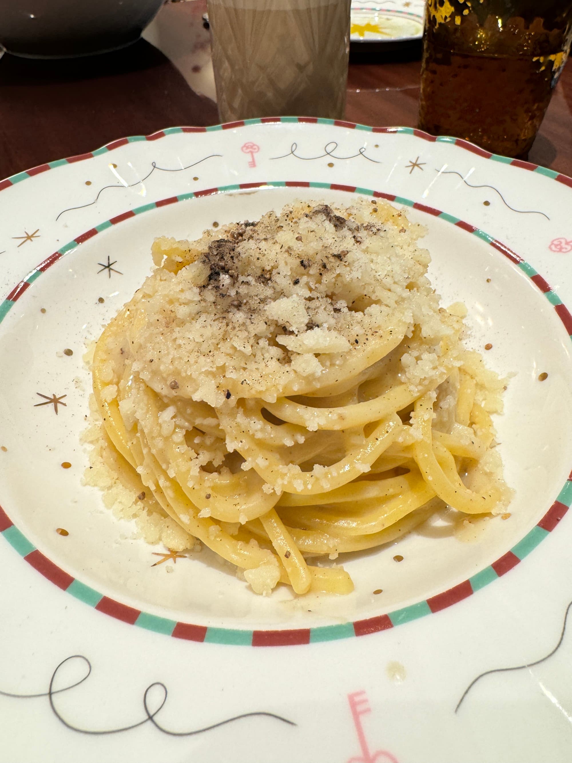 A food view of a plate of pasta piled high with parmesan cheese on a white plate.