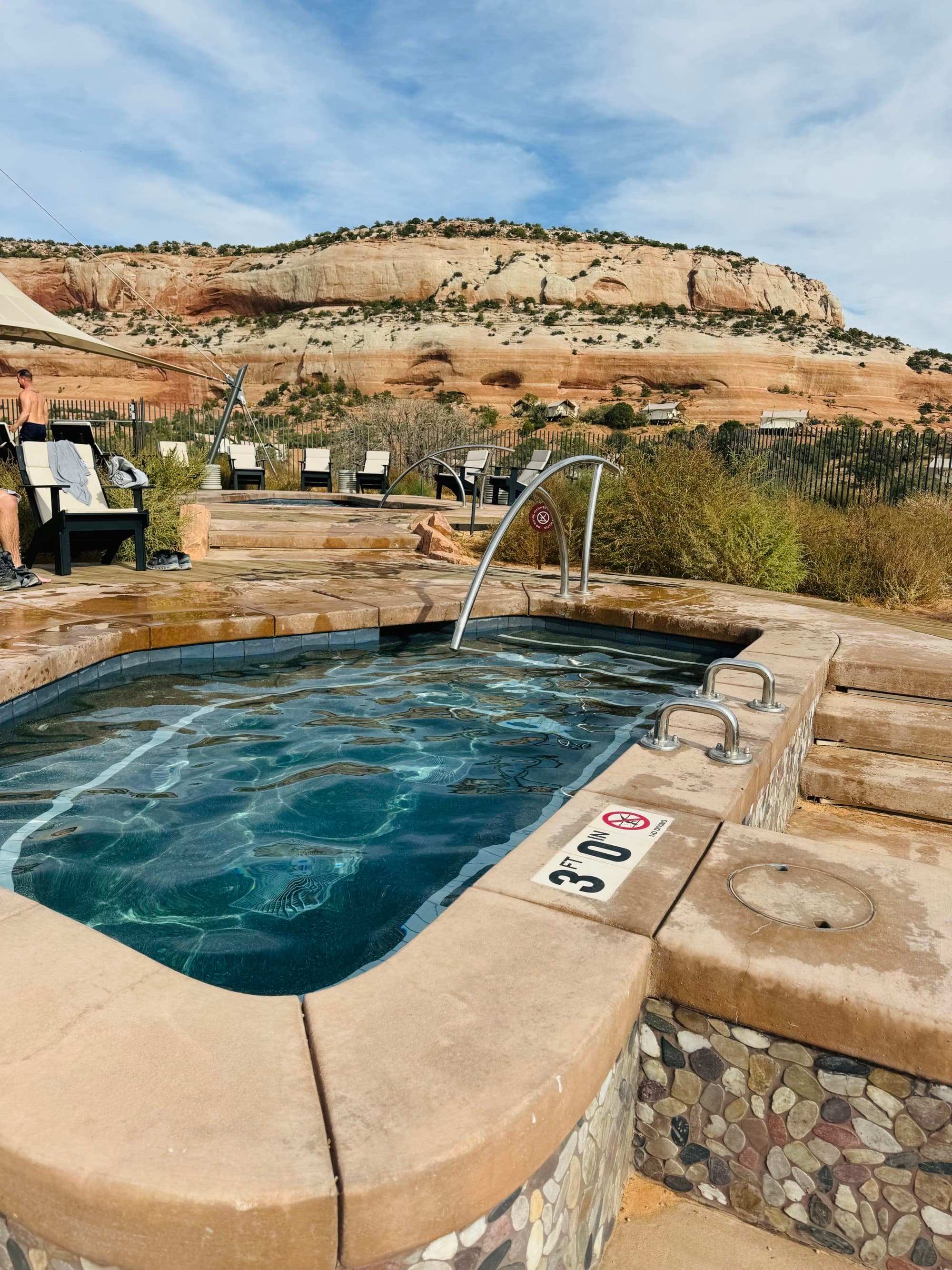 A view of a small pool surrounded by a desert landscape during the day.