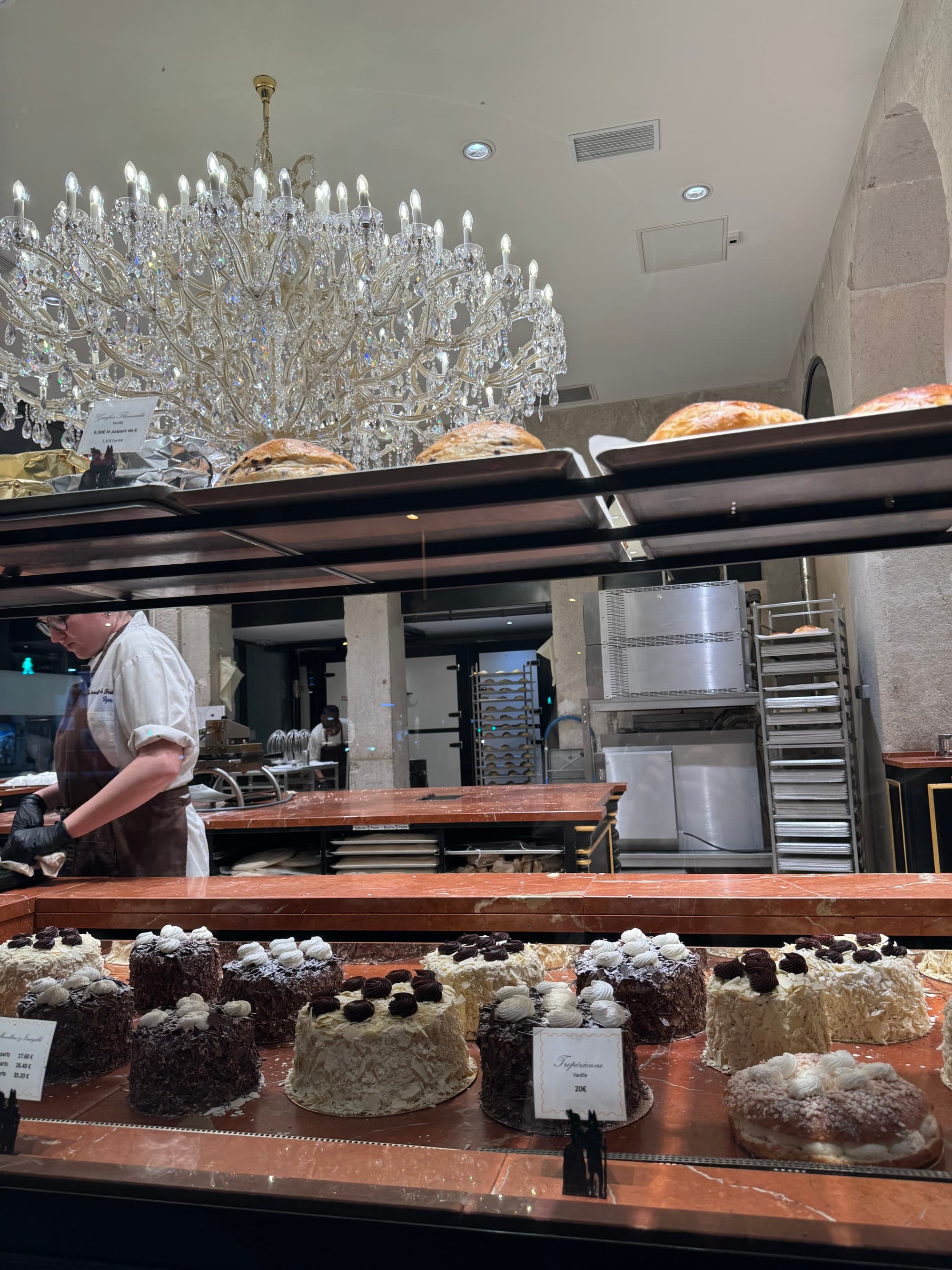 Buffet table filled with desserts and a chef in the background with an ornate crystal chandelier overhead.