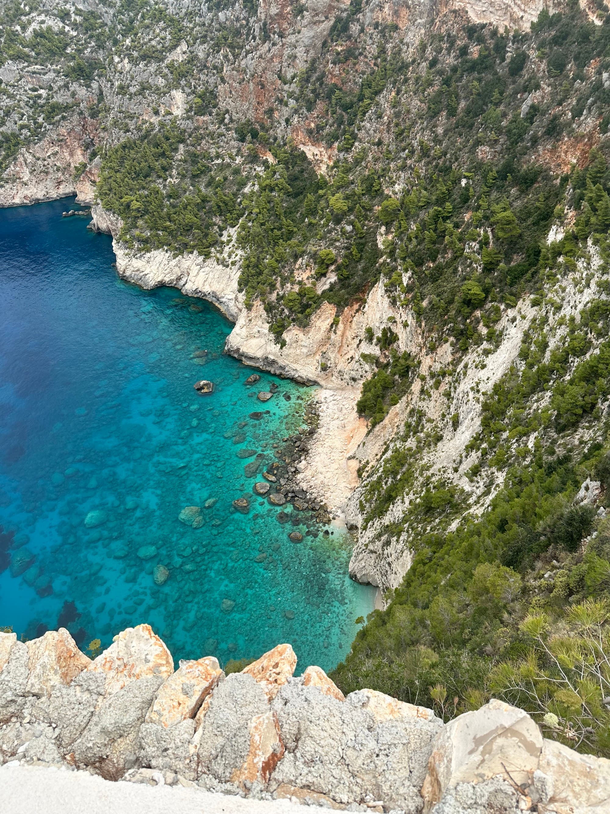 View of crystal-clear waters from a hillside cliff view on a sunny day.