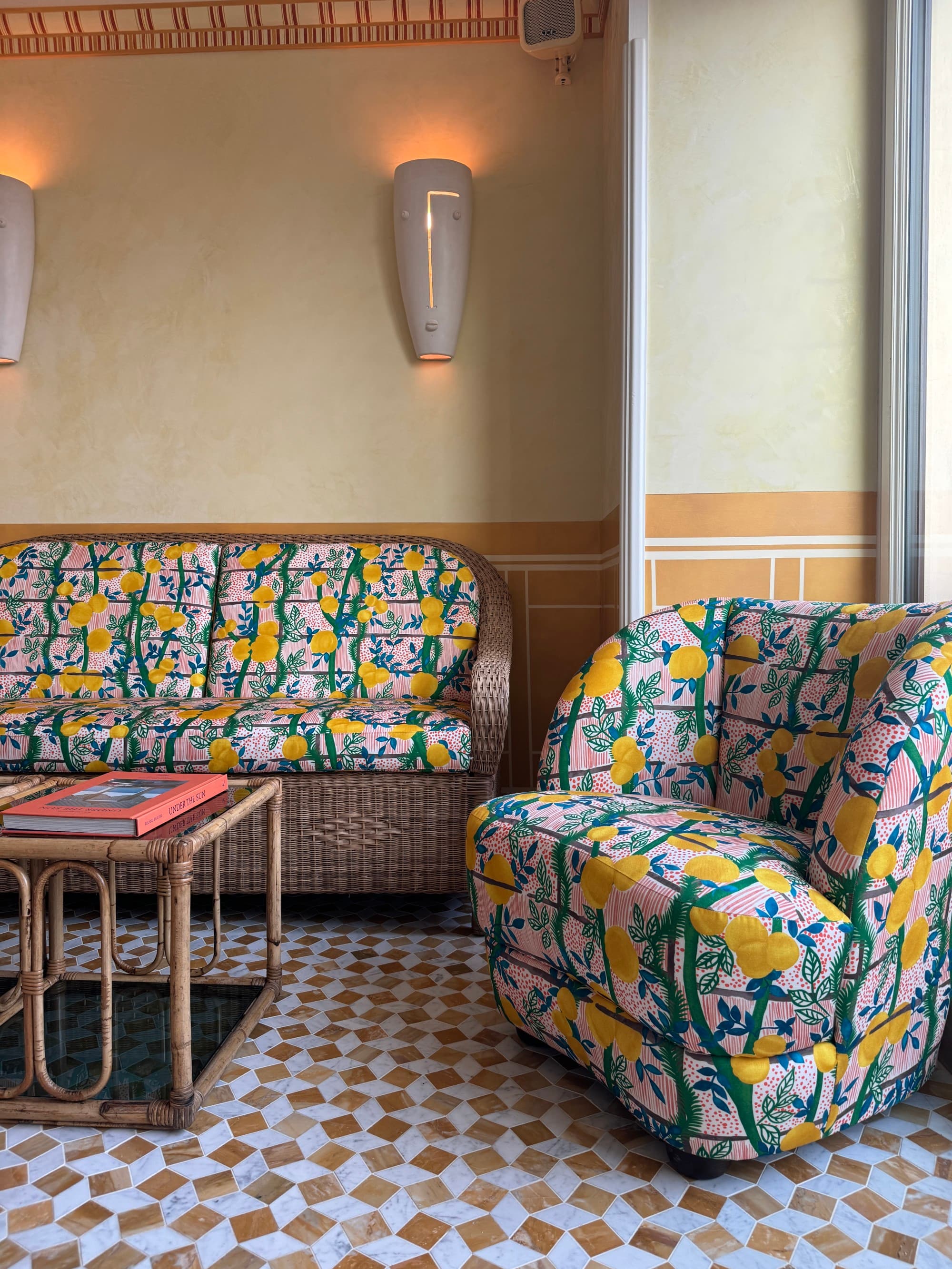 A sitting area with gold and white diamond tiled floors, a chair, couch and table.