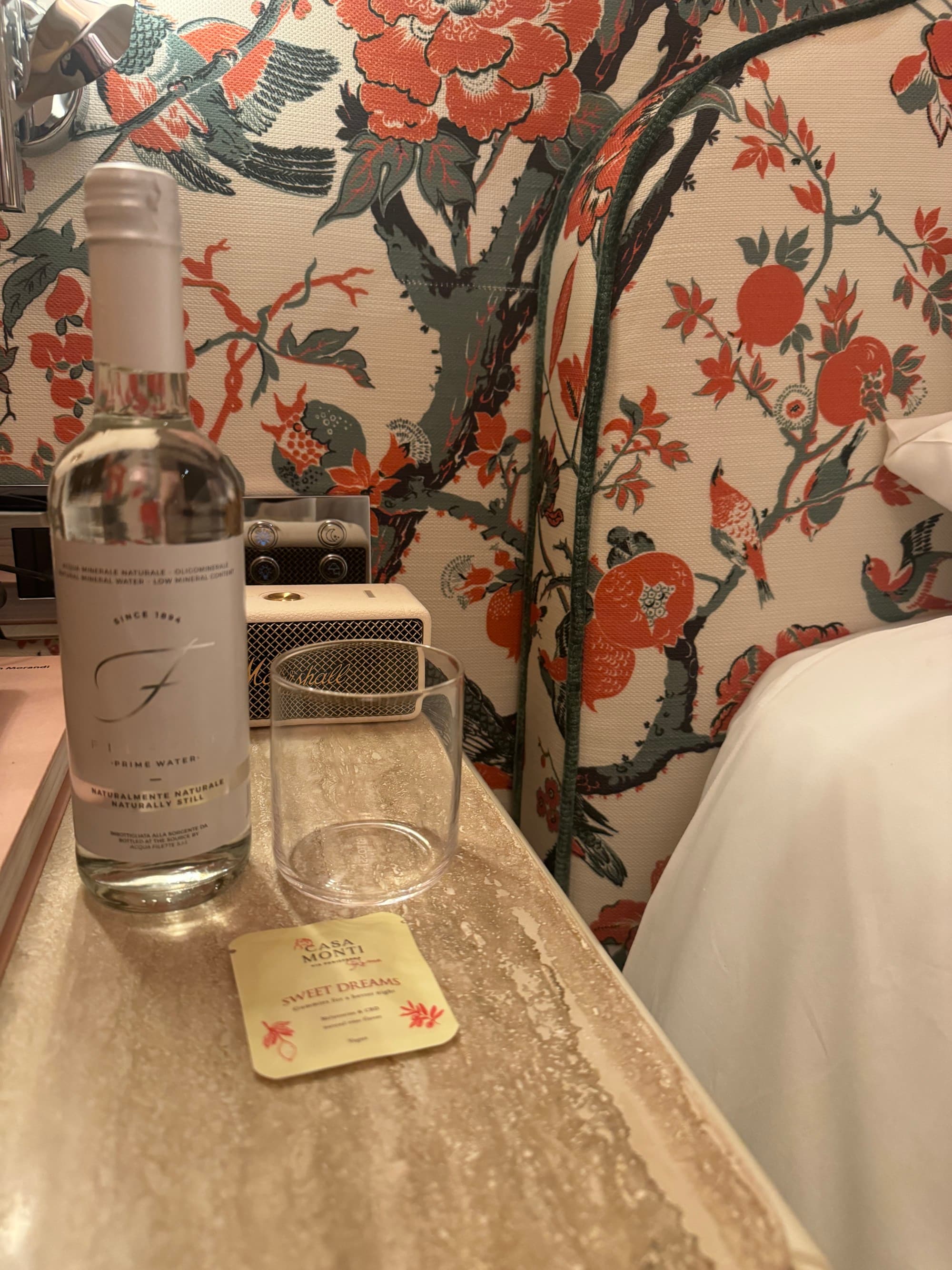 A view of a wine bottle and a glass on a table near the bed in the hotel room.