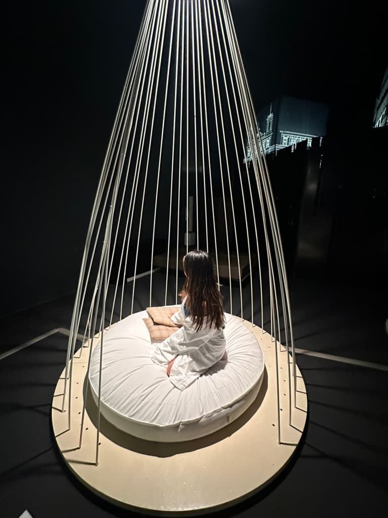 A person sitting in the center of a chair in a dimly lit room