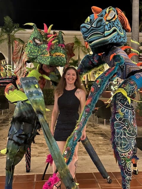 Travel advisor posing with two bright colored sculptures.