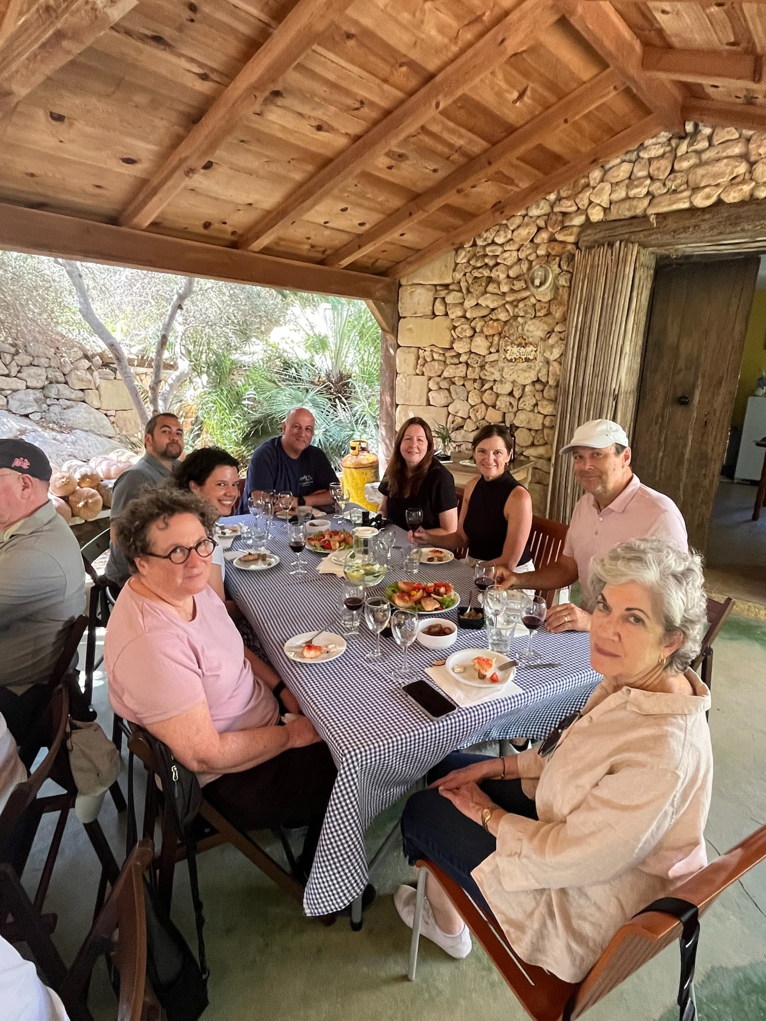 A group of people at an outside table looking at the camera for a photo