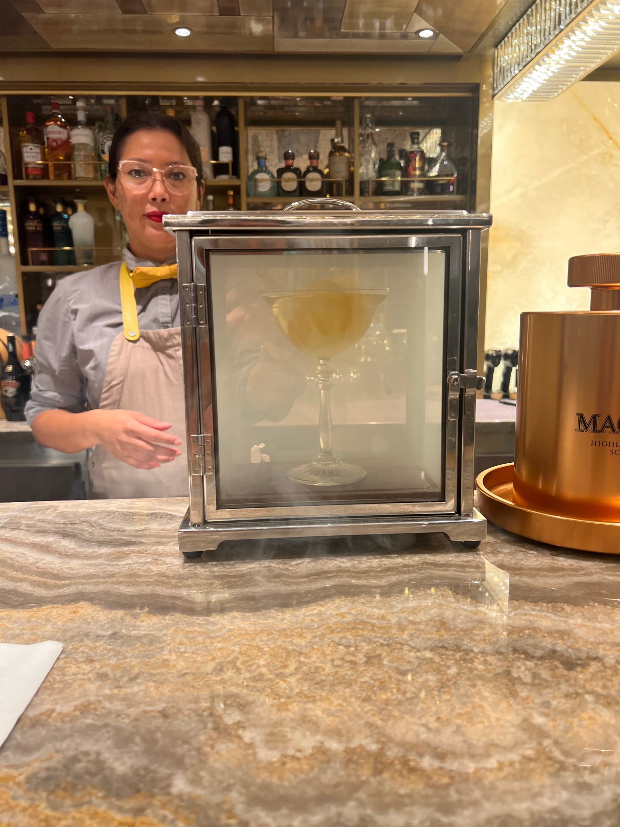 A person behind a bar presenting a drink in a box