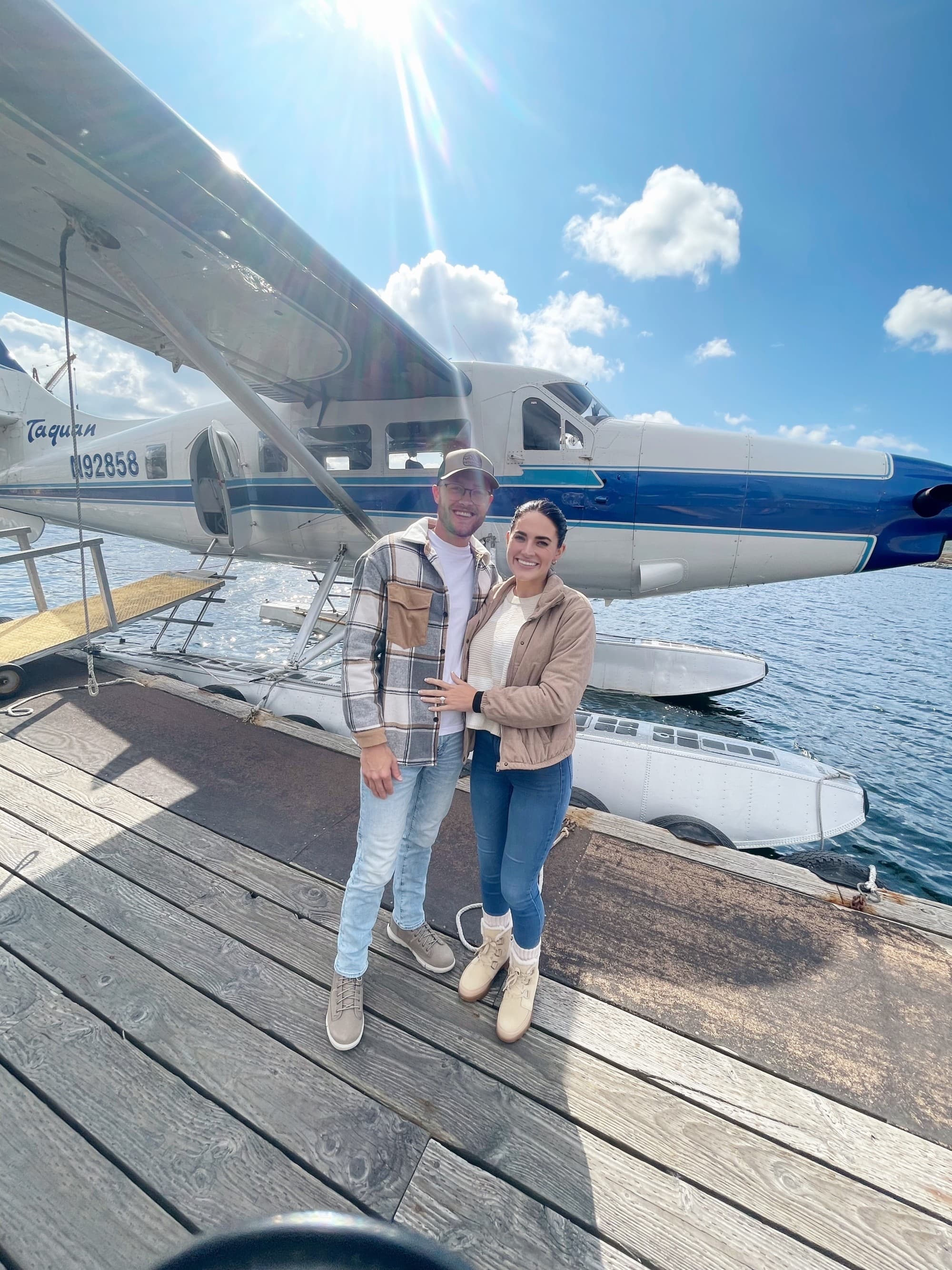 Two people standing and posing for a photo together in front of a sea plane